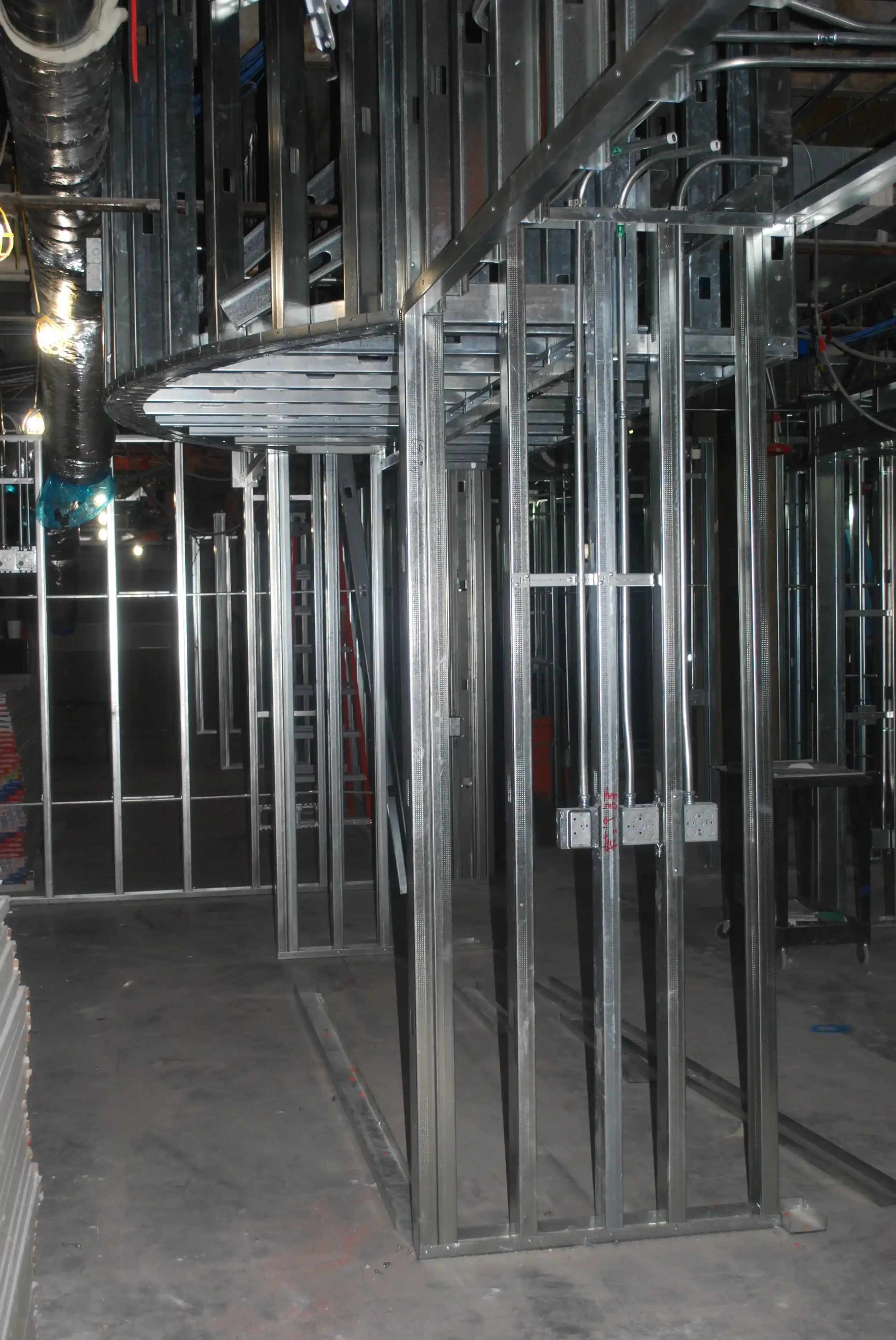 Steel framing for a building under construction, showing metal studs and a suspended metal ceiling framework.