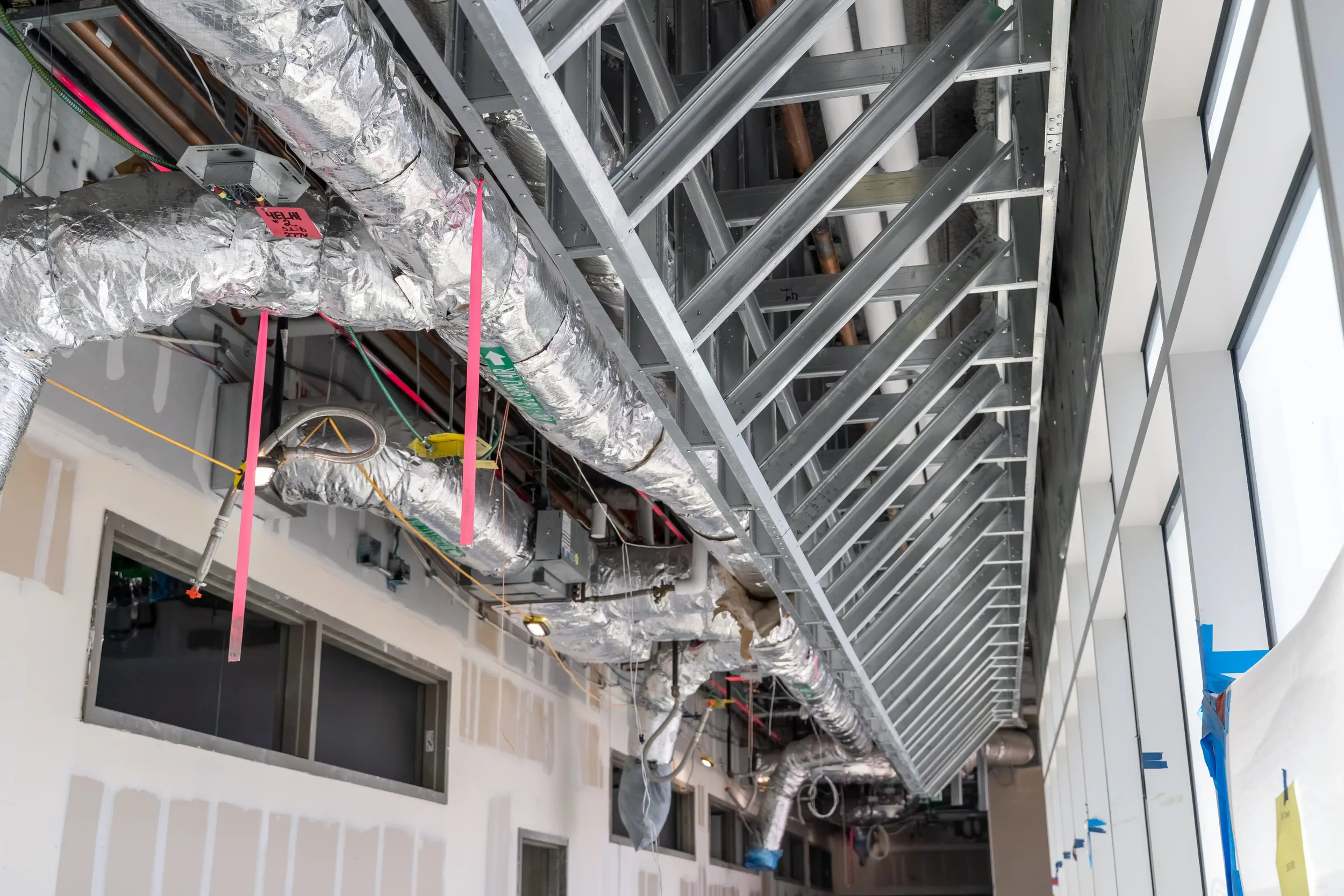 Construction site interior with metal framing, ductwork, and building materials.