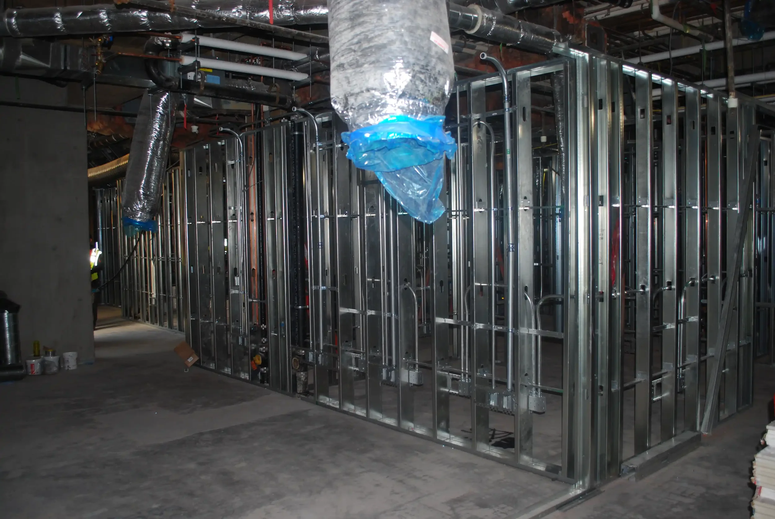 Construction site showing metal framing and ductwork installation in progress.