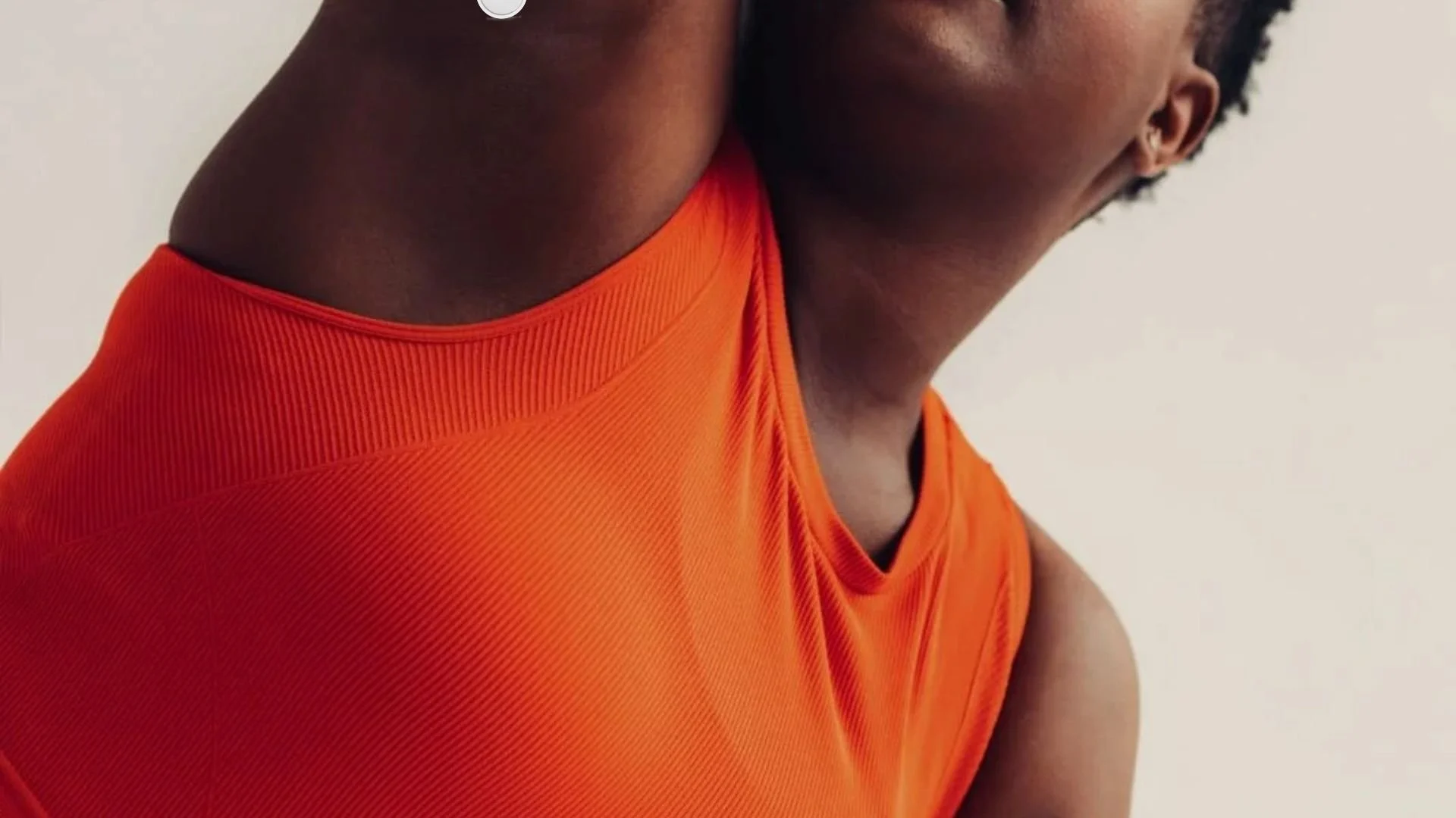 Person wearing ONETRIBE athletic apparel in orange tank top representing active Type 1 diabetes lifestyle and fitness confidence