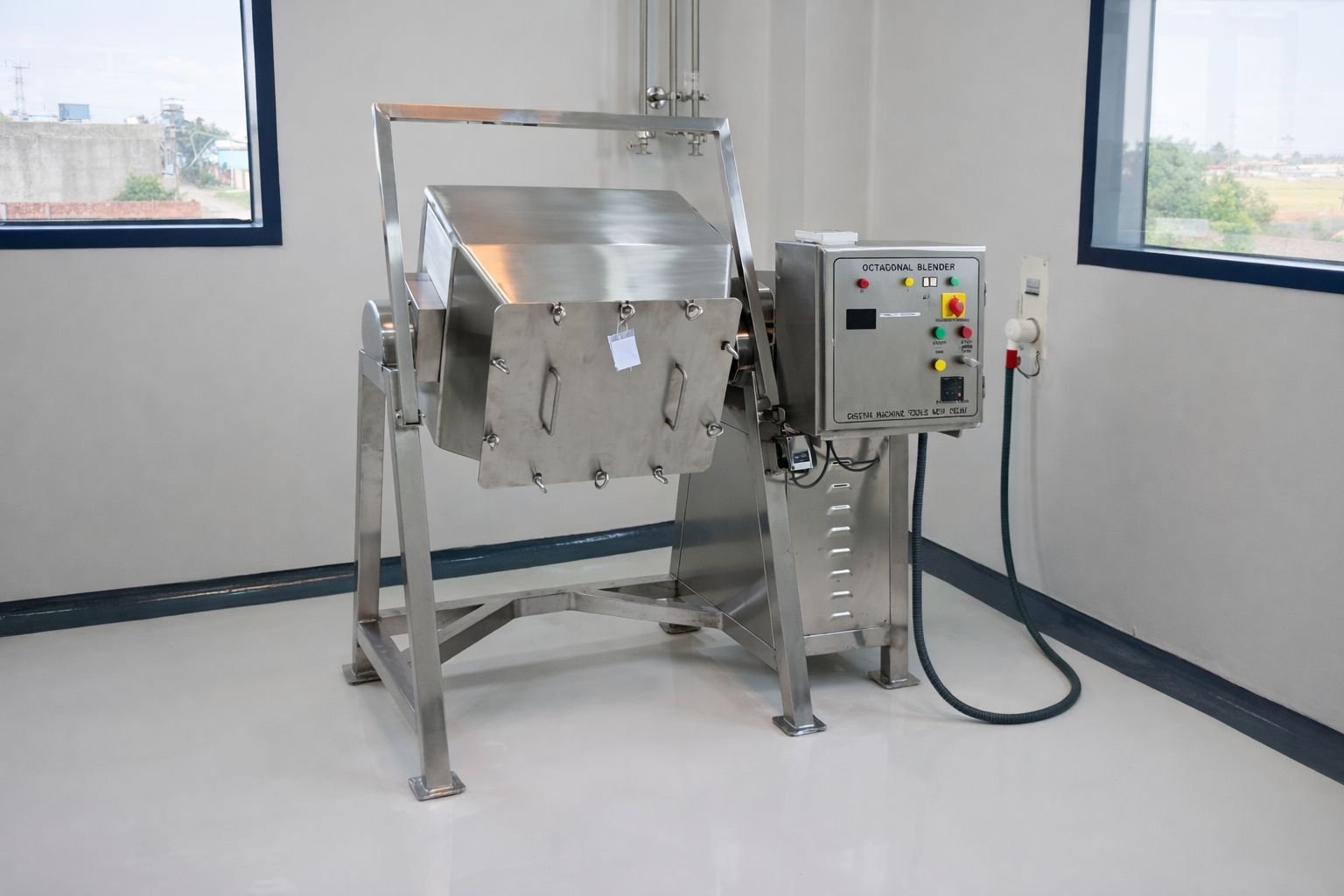 Industrial machine with a stainless steel chamber and control panel, located in a room with white walls and large windows.