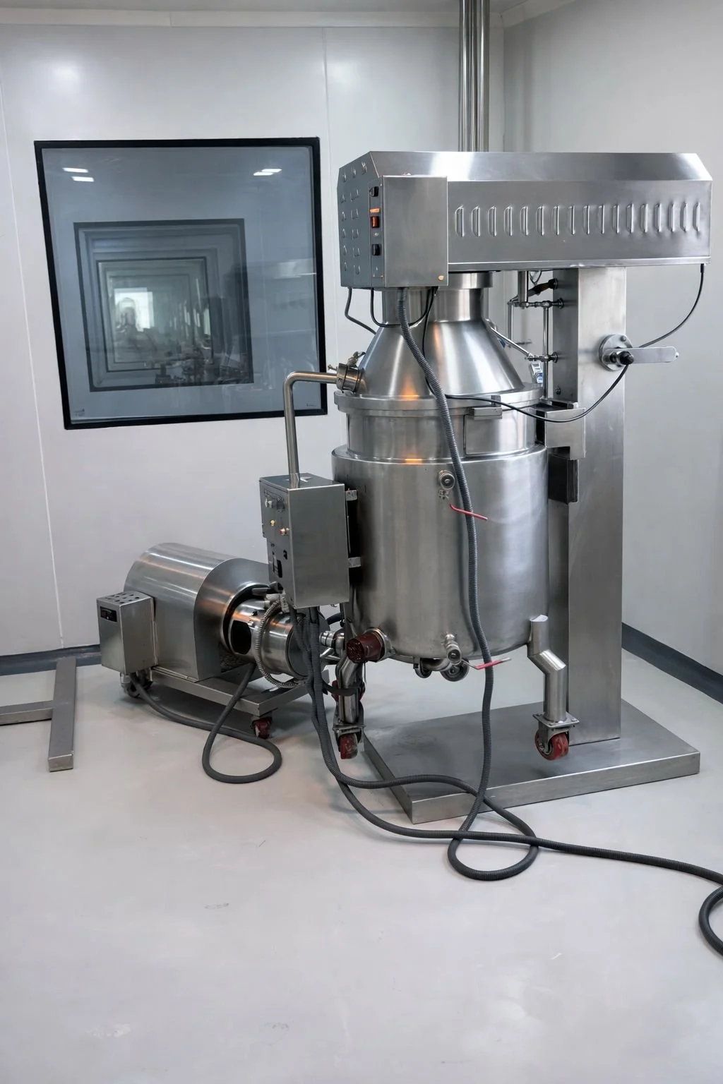 Industrial stainless steel vacuum chamber with attached motor and control panel in a clean room setting.