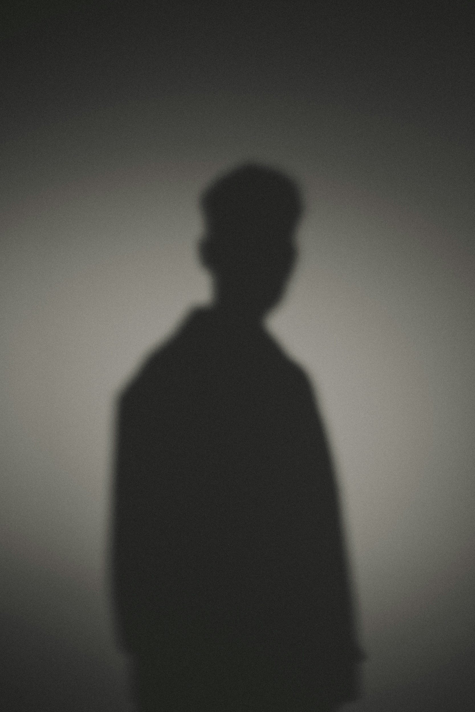 Silhouette of a person against a blurred background, with no discernible details.