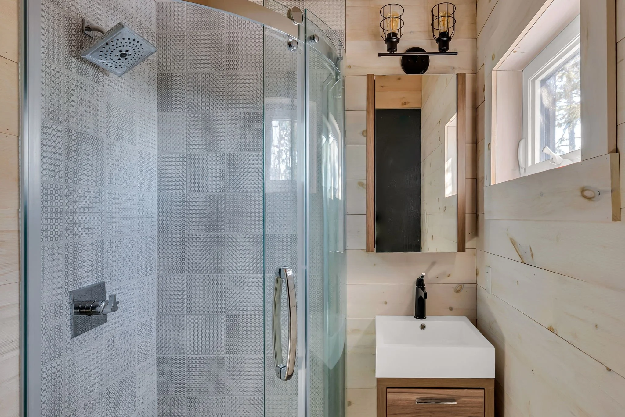 Modern bathroom with glass shower and wood vanity in a ontario cottage custom home