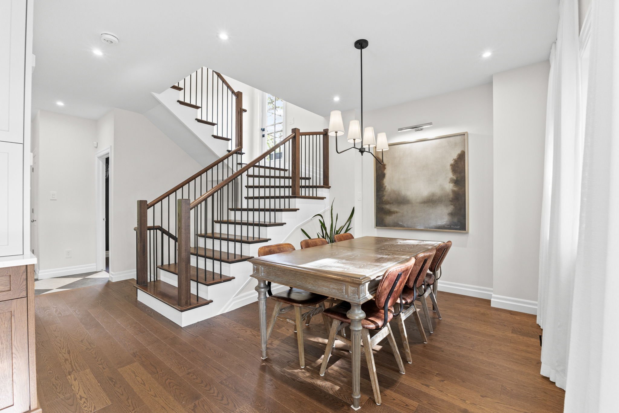 Custom home interior in Kanata featuring a thoughtfully designed dining area, statement lighting, and a wood staircase with black metal railings, built with attention to detail by a trusted Kanata builder.