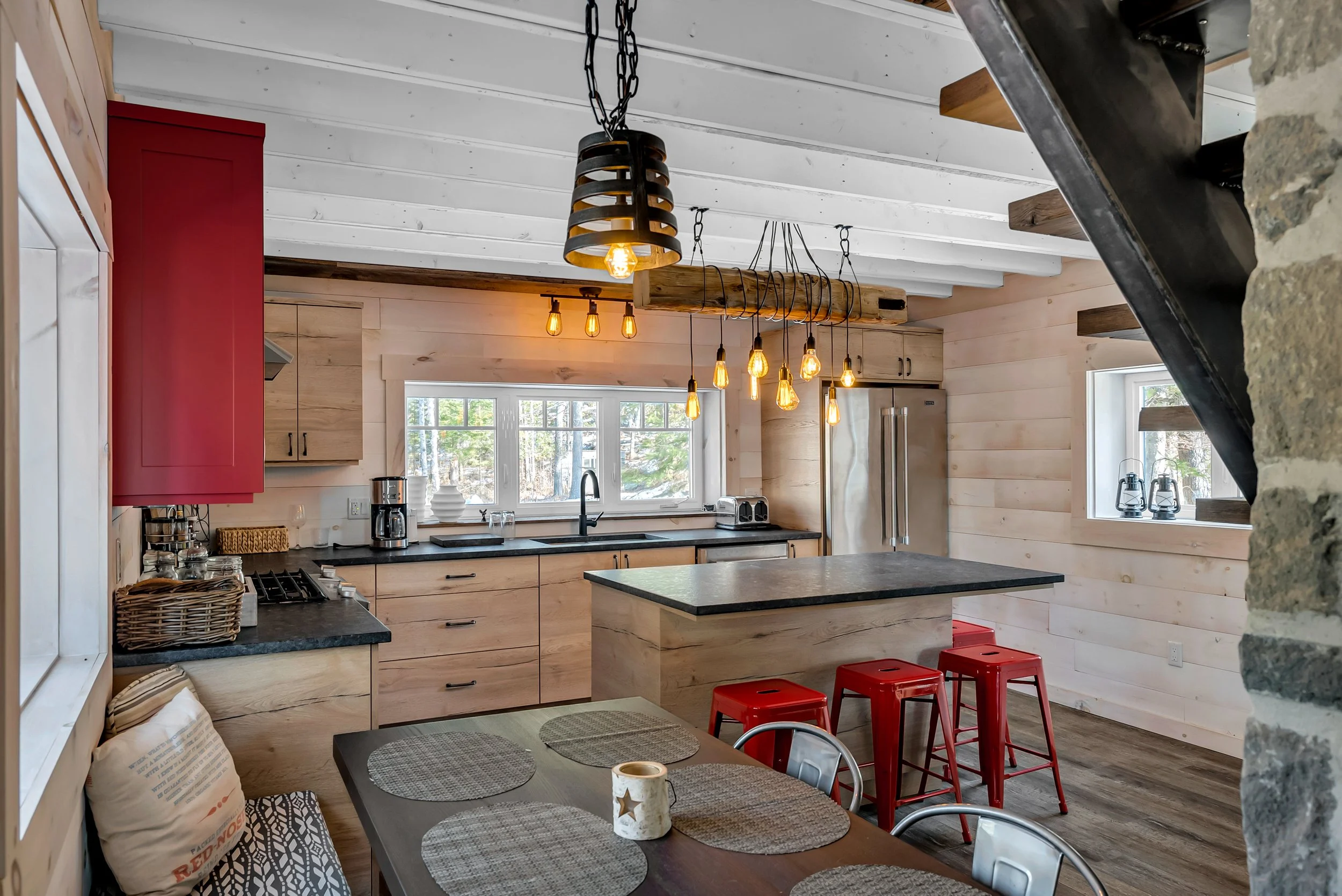 modern kitchen in Ottawa featuring wood cabinetry and wall paneling, black countertops, a large window, and a central island with seating, designed by Centennial Construction Management.