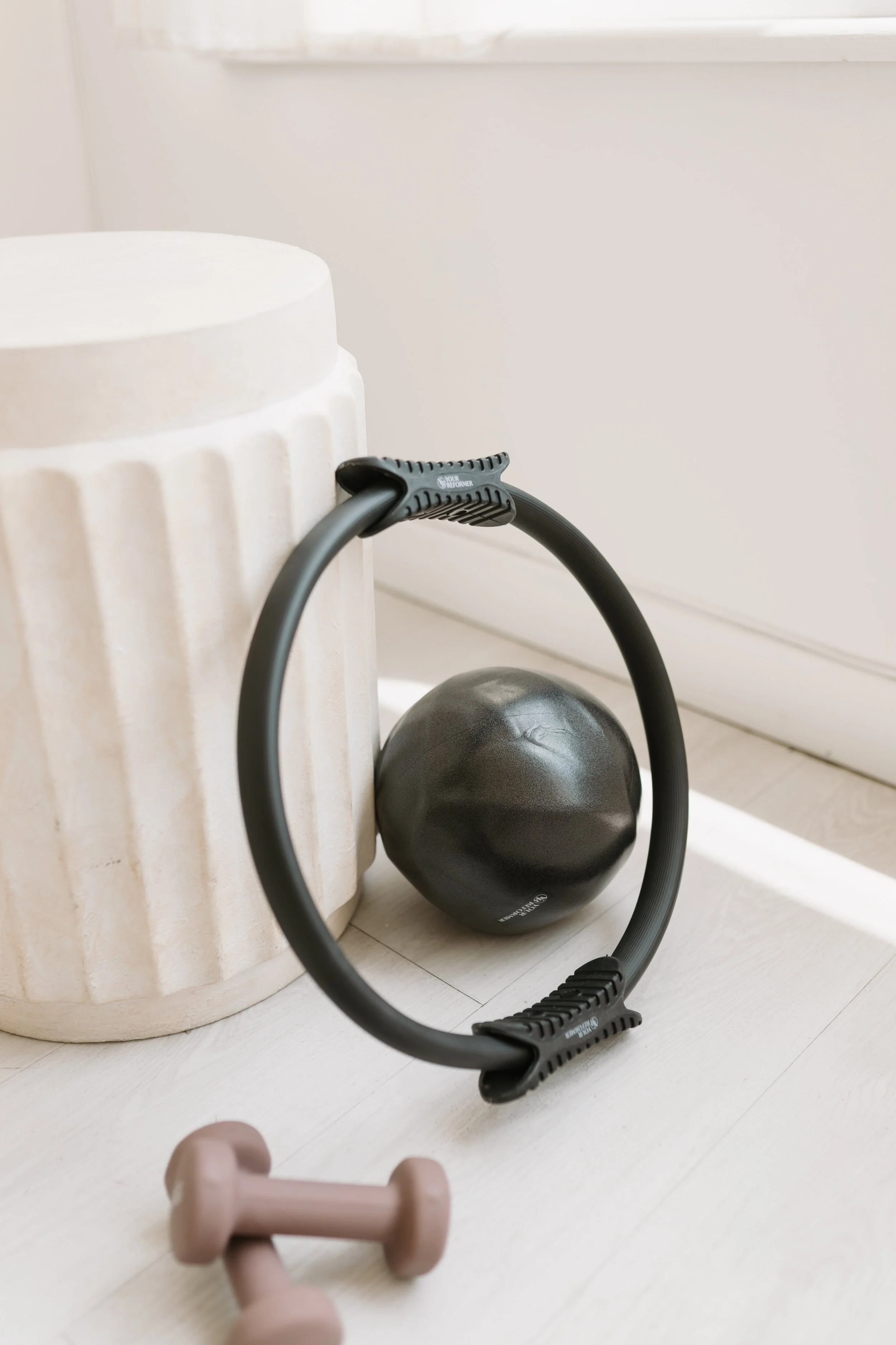 An aesthetic detail photograph of pilates equipment including dumbbells, a pilates ring, and an exercise ball from Worth It: A Reformer Pilates Studio in Keller, Texas, near Dallas, Texas.