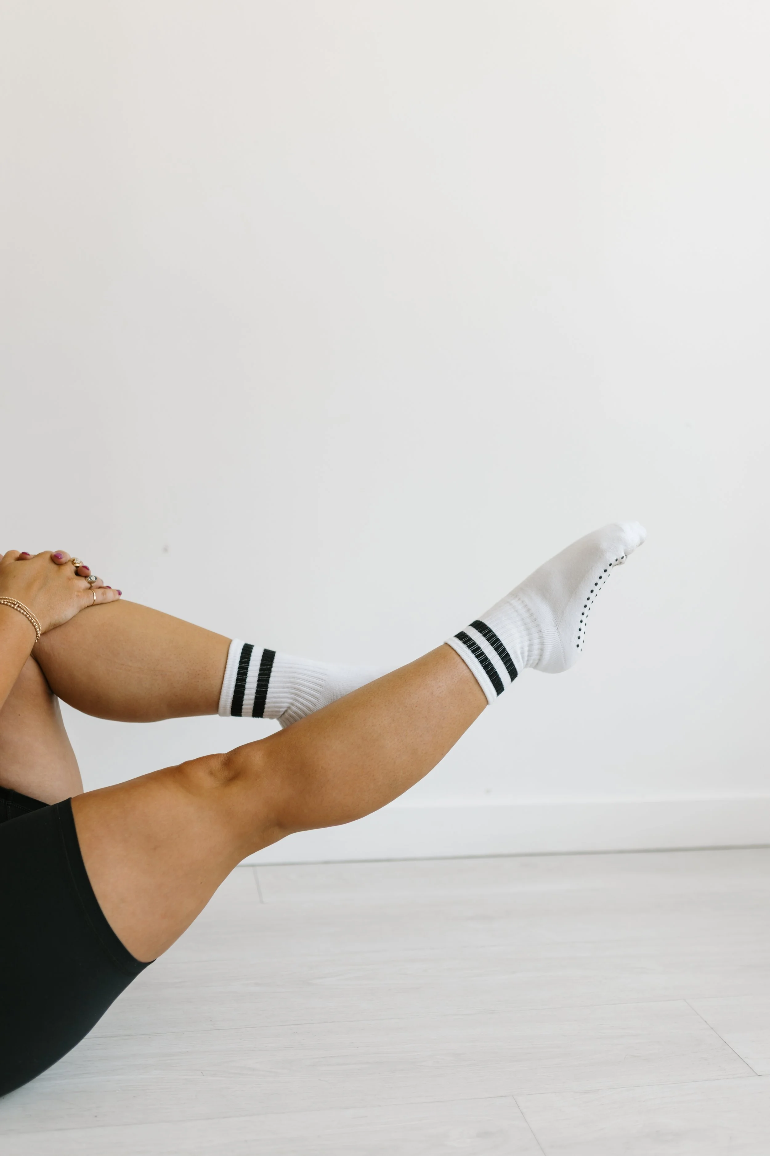 Person wearing white socks with black stripes and black shorts holding a pilates pose with their leg elevated at 45 degrees at  Worth It: A Reformer Pilates Studio in Keller, TX, near Dallas, TX & Fort Worth, Texas.