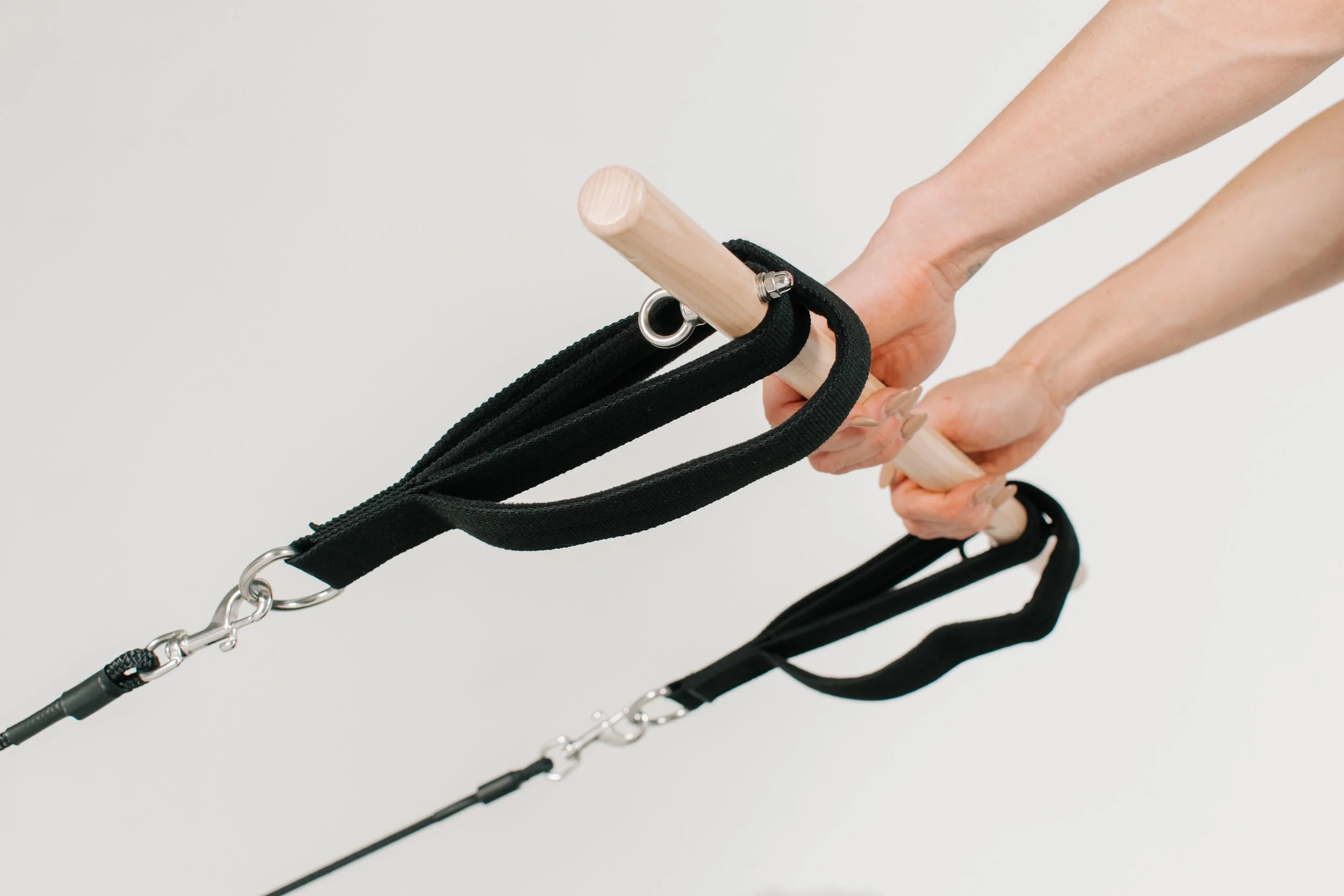 Photograph of tan individual using the straps and wooden bar on the luxury reformer used during the group reformer pilates classes at Worth It: A Reformer Pilates Studio located in Keller Texas, near Dallas, Texas and Fort Worth, Texas. The studio ho