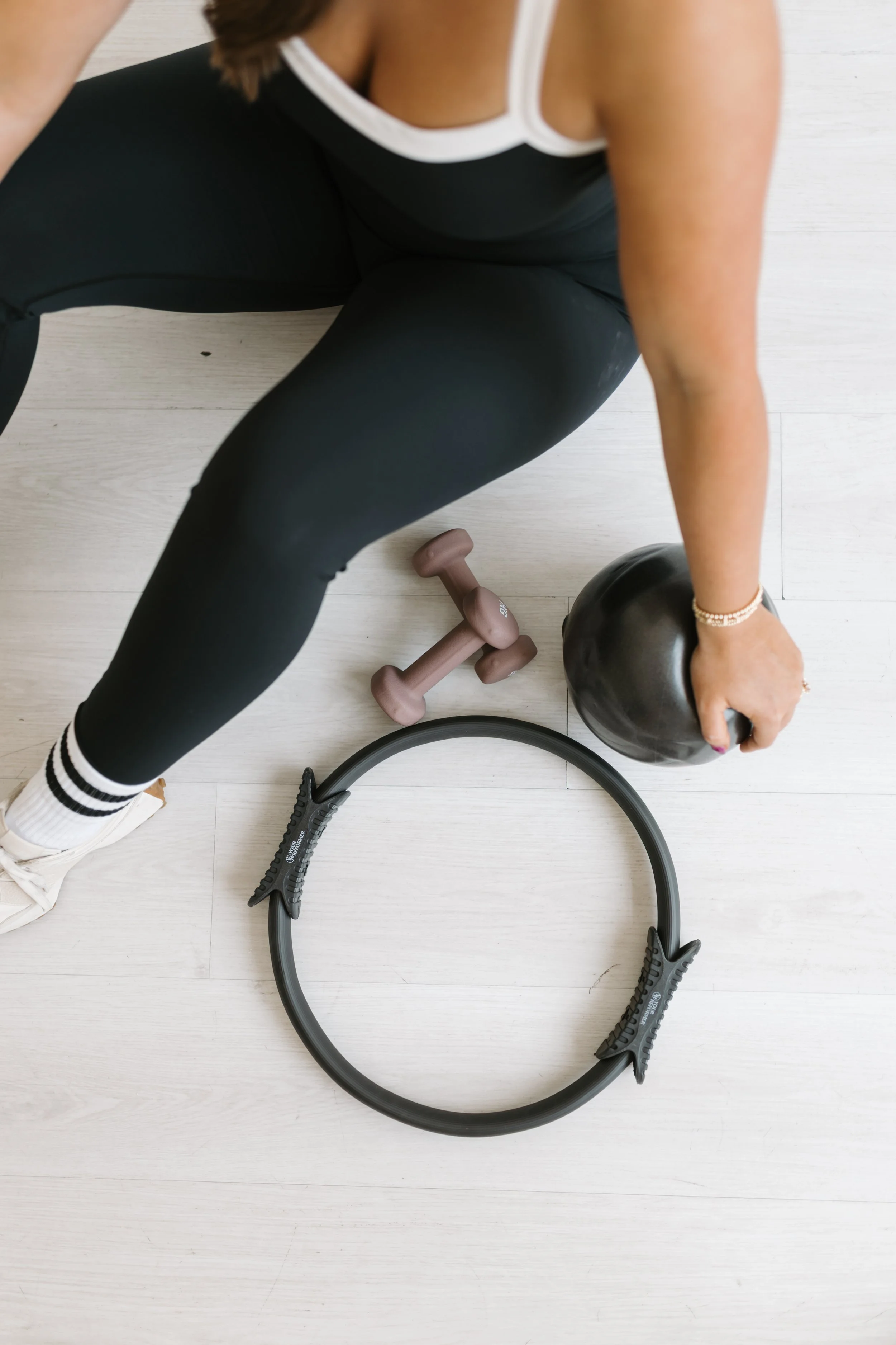 A birds eye photograph of someone in black workout clothes sitting with pilates exercise equipment at Worth It: A Reformer Pilates Studio located in Keller Texas, near Dallas, Texas and Fort Worth, Texas.