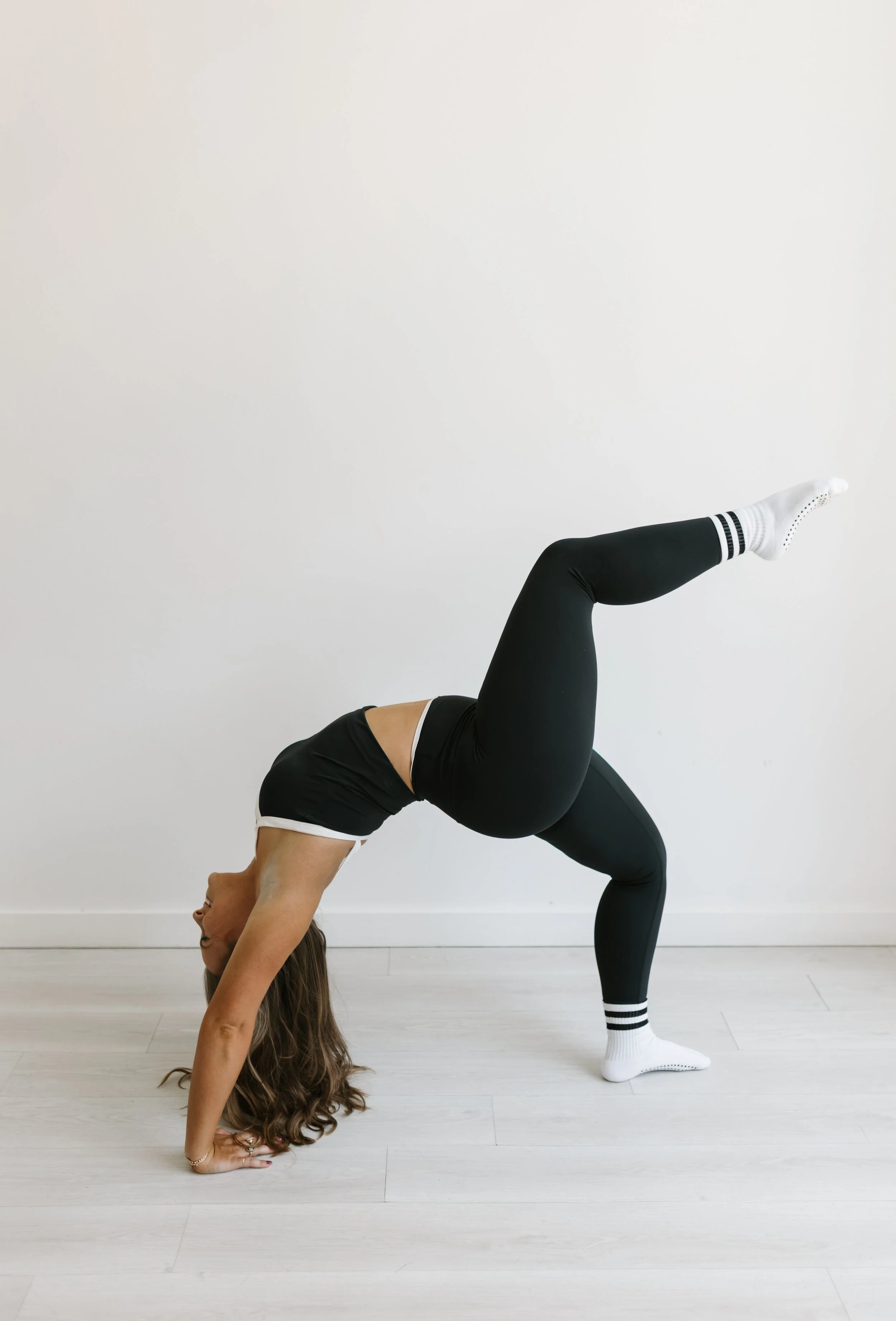 A picture of a woman in black workout attire doing a bridge with an elevated leg atWorth It: A Reformer Pilates Studio in Keller Texas