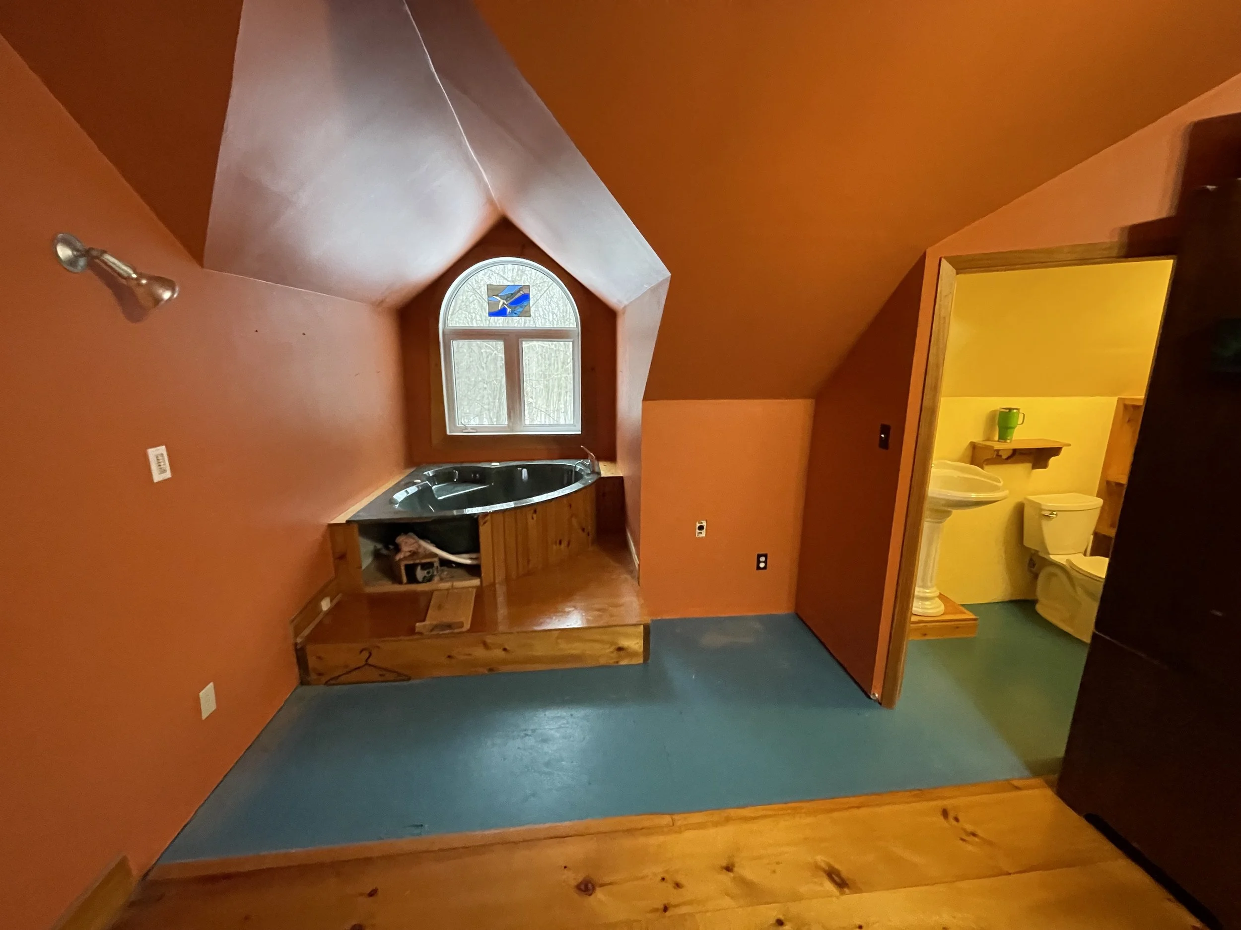A small bathroom with orange walls and a sloped ceiling. Before the bathroom renovation photo.  Tile Work and Contractor Kawartha Lakes, GTA, Muskokas.