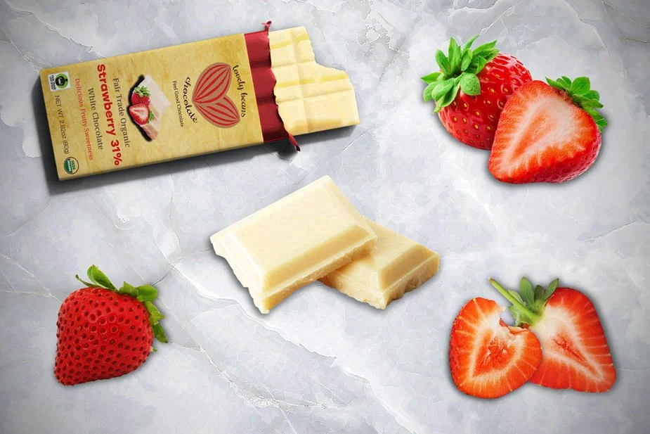 Organic strawberry white chocolate bar and white chocolate pieces surrounded by fresh strawberries on a textured surface, highlighting delicious flavors.