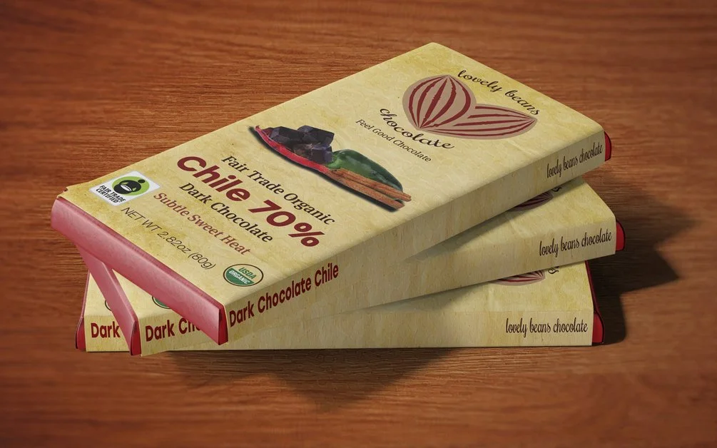 Stack of three Lovely Beans Organic Fair Trade 70% dark chocolate bars with chile flavor on a wooden surface.