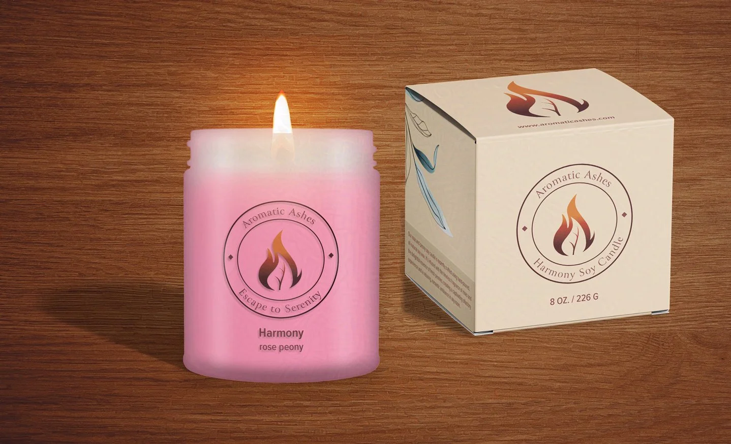 Lit pink "Harmony" rose peony scented soy candle next to its beige Aromatic Ashes branded packaging box on a wooden surface.