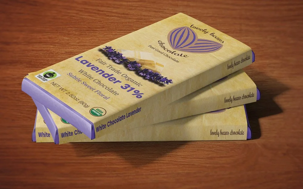 Three bars of Lovely Beans chocolate, labeled as Fair Trade Organic Lavender 31% White Chocolate, are stacked on a wooden surface.