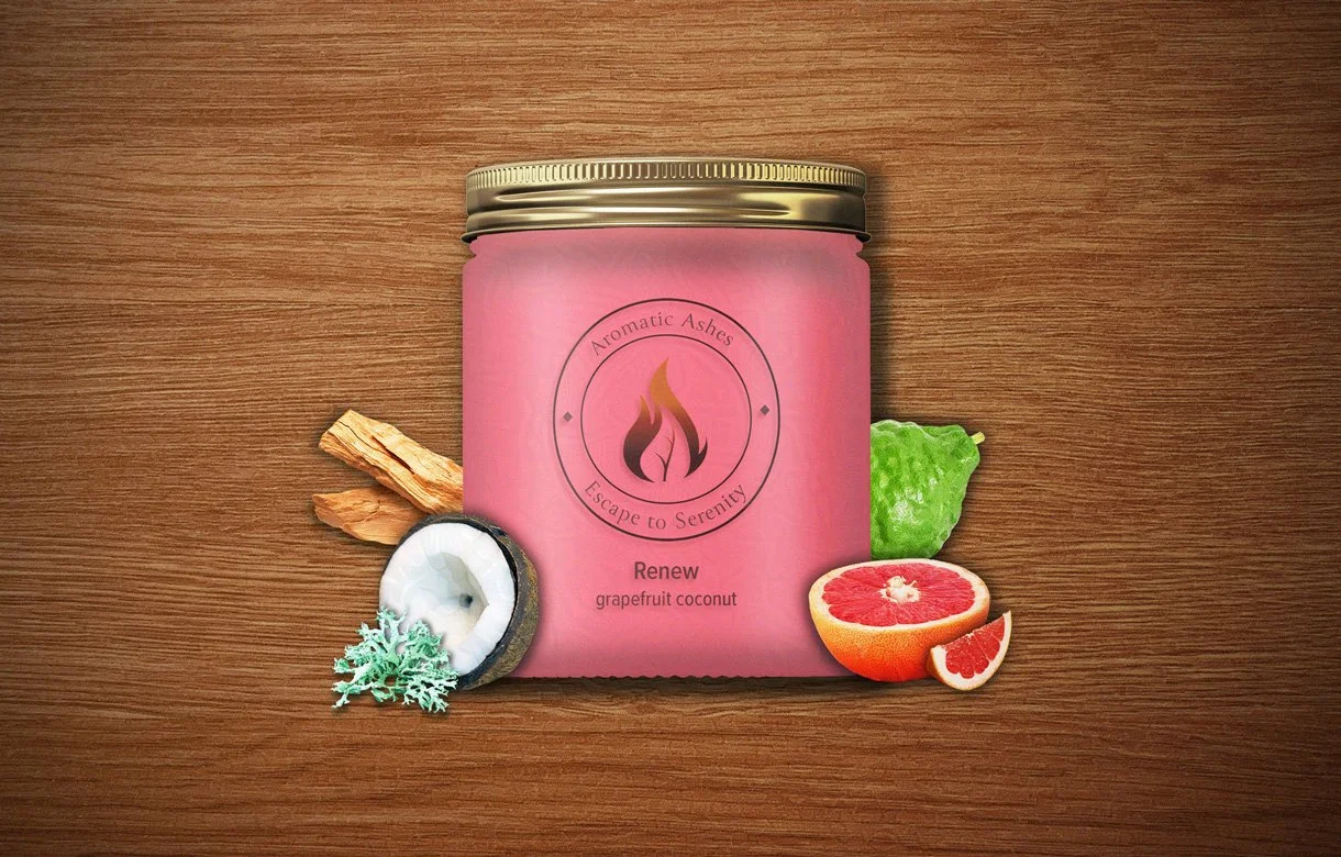 Pink Aromatic Ashes candle jar labeled "Renew grapefruit coconut" with grapefruit, coconut, sandalwood, oak moss, and bergamot on a wooden surface.