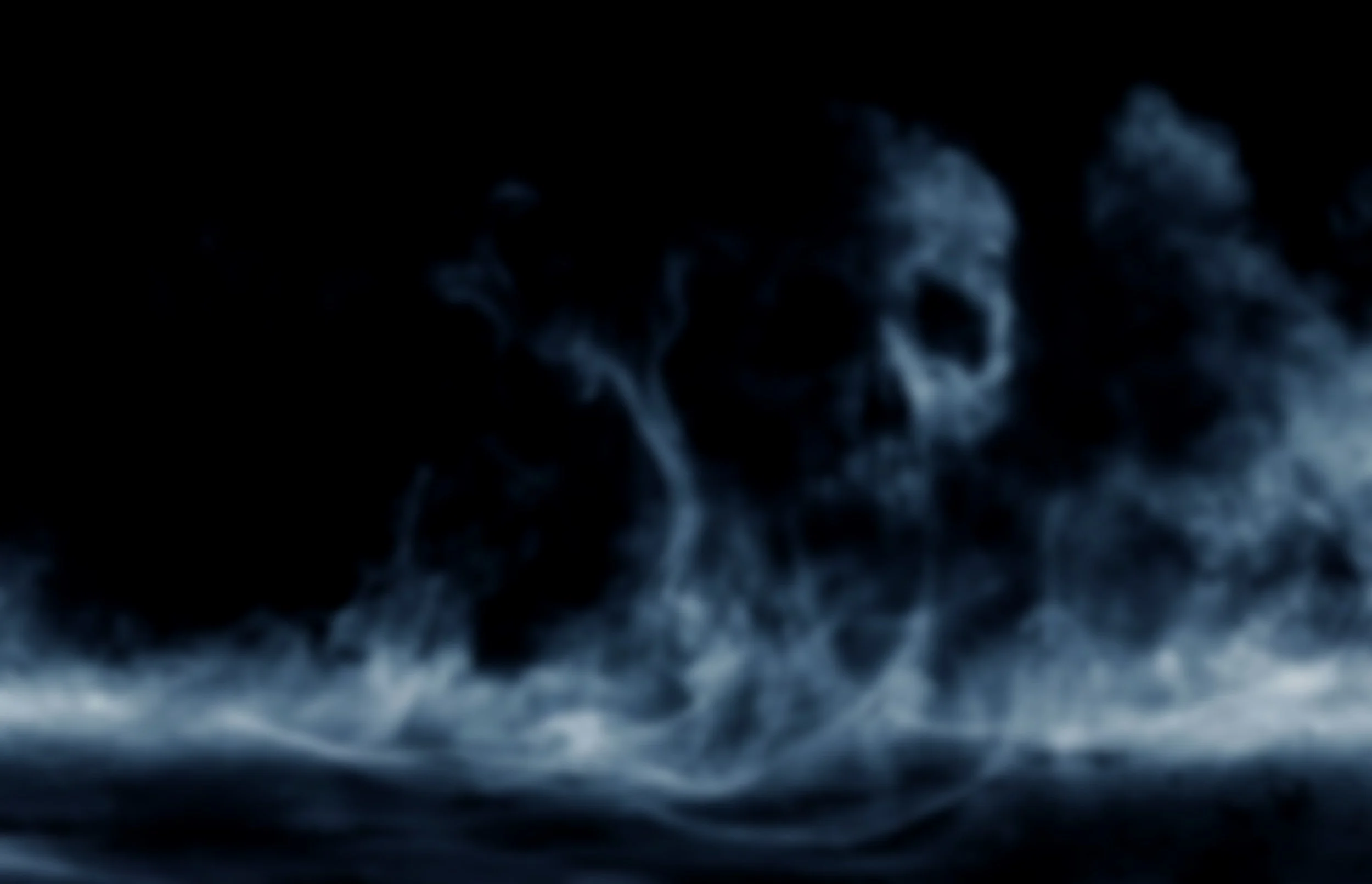 Eerie blue-gray smoke forms a ghostly skull above a dark, mist-covered landscape, creating a haunting, mysterious atmosphere.