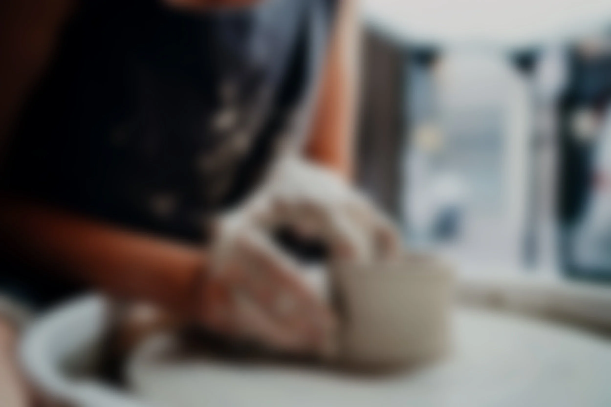 Close-up of hands shaping a clay pot on a pottery wheel in a workshop.