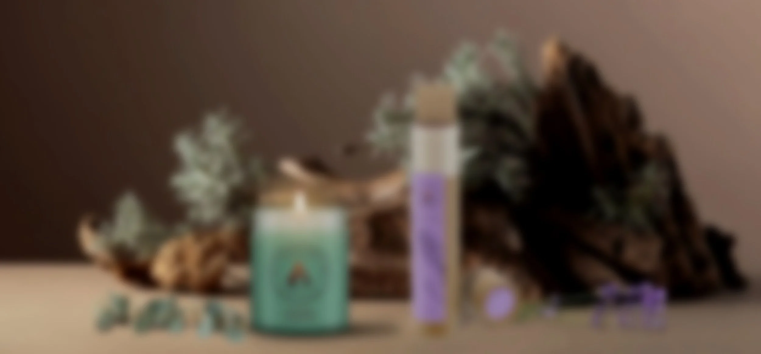 A serene scene with a lit teal candle and lavender incense sticks beside driftwood and leafy sprigs. Purple lavender flowers and eucalyptus leaves add a calming touch.