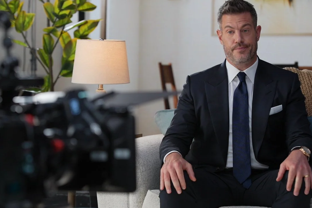 TV Personality Jesse Palmer sitting on a couch in a living room, being filmed by a camera at AMS Pictures.
