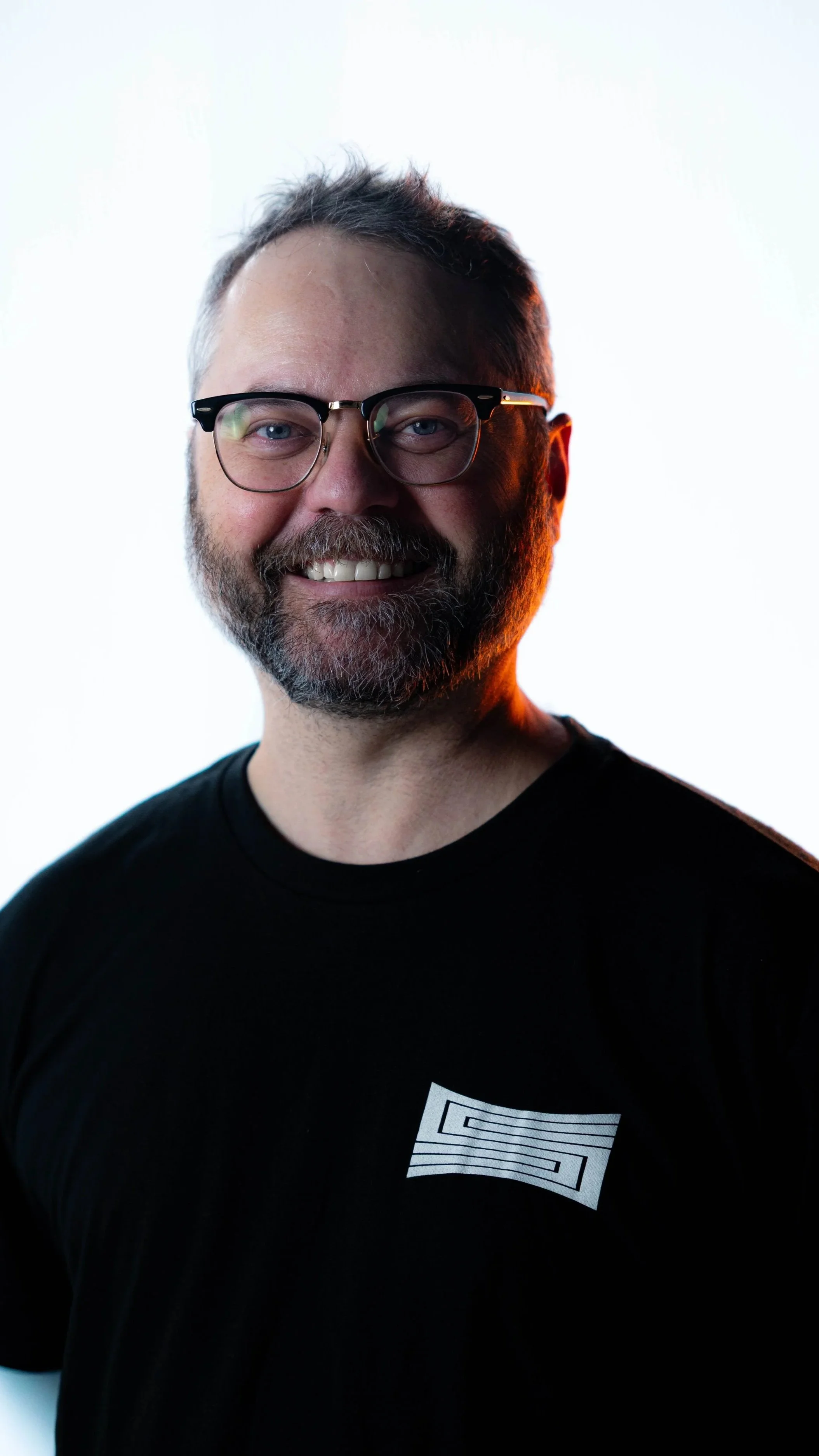 Virtual Production Supervisor, Tanner Griggs, wearing a SHOTCALLER shirt against a white background with lighting effects.