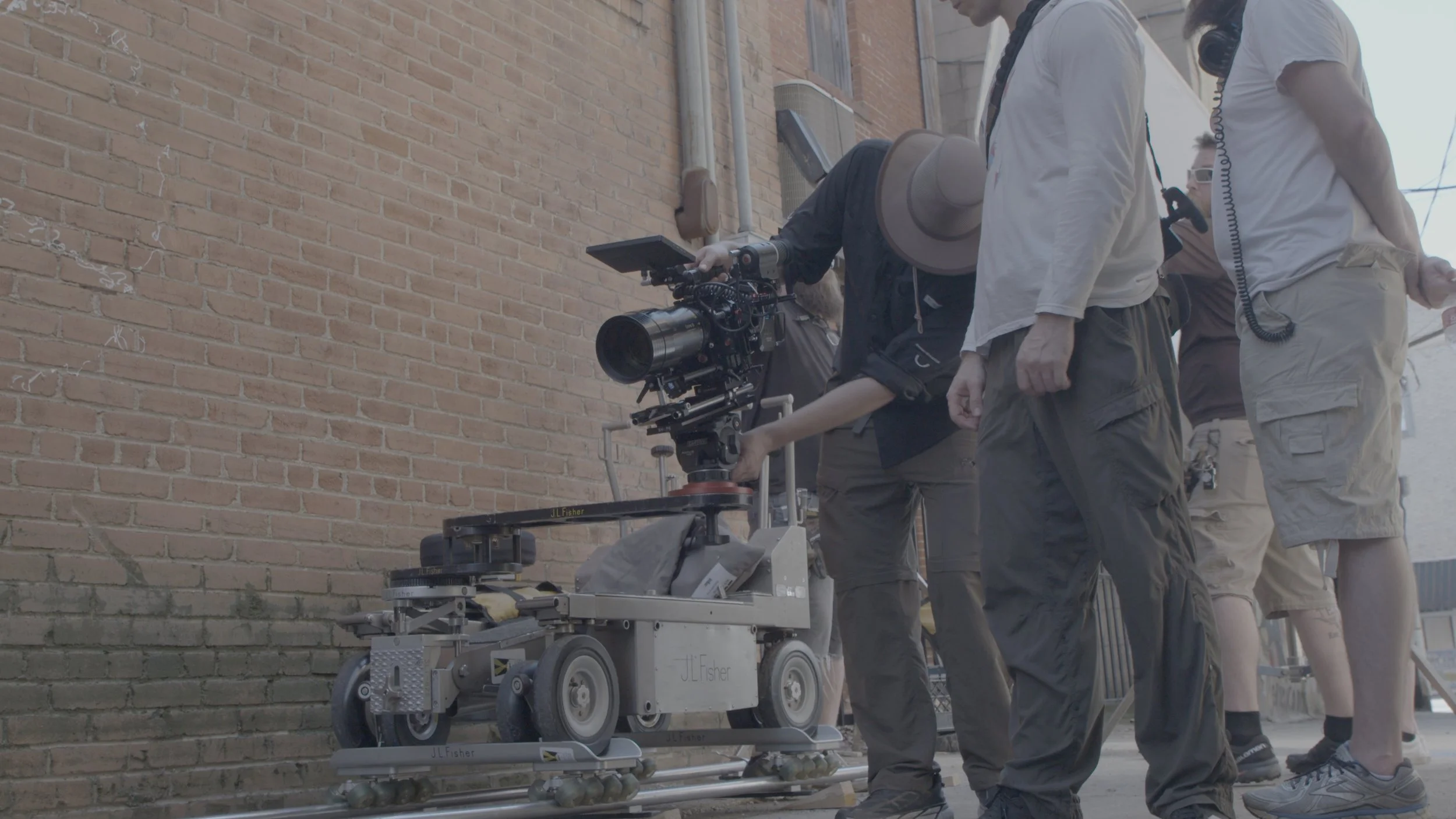 Film crew operating camera setup on a city sidewalk.