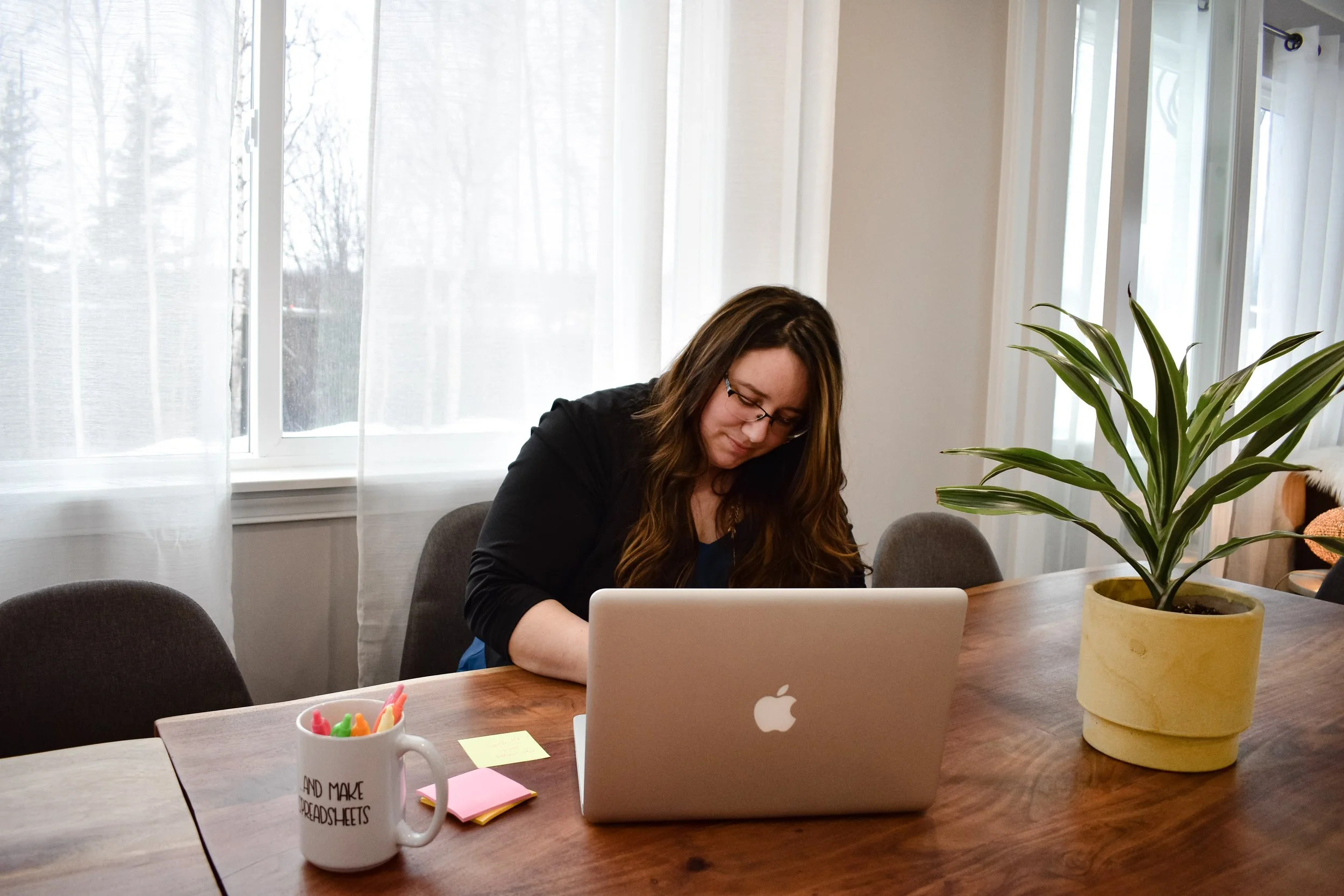 Robin Angaiak owner of line and ledger writing with her laptop at her desk on sticky notes