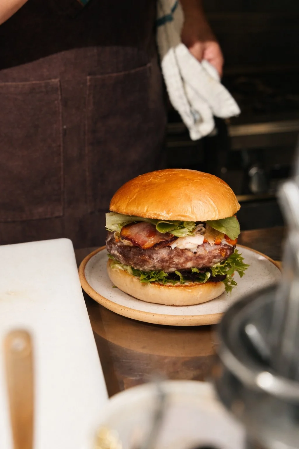 Chilli cowboy hamburger med kjøtt, bacon, salat, tomat og saus, cheddar på en tallerken. - Rolis Bodega, Nordstrand, Oslo