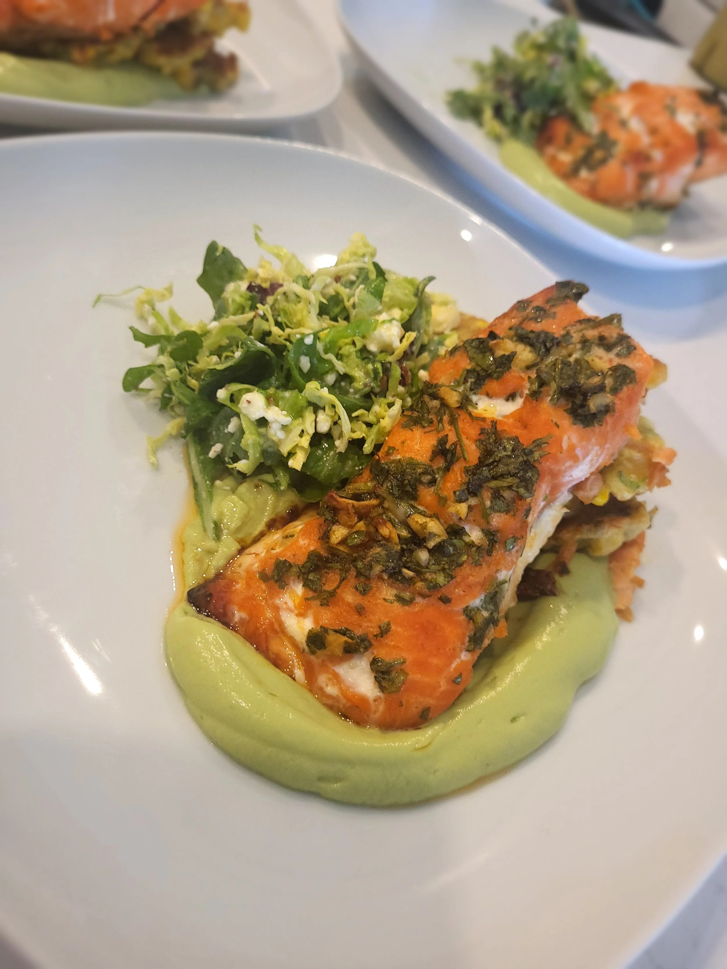 Pesto crusted salmon w/ avacodo crema, corn & scallion fritters, apple & brussel sprouts slaw