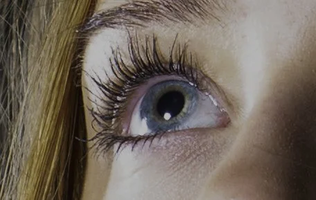 Close-up of a woman's eye with long eyelashes and visible makeup.