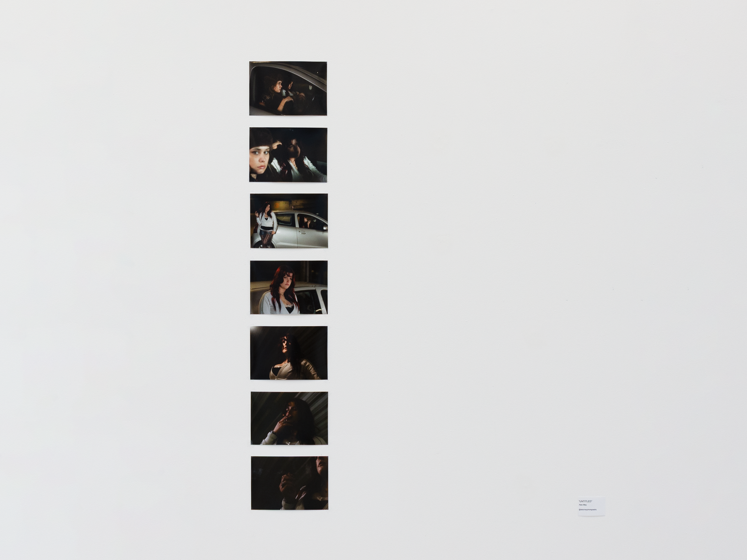 A vertical series of photographs on a white wall showing women in urban settings, each with different poses and expressions, with one woman smoking and another standing next to a car, in dark lighting.