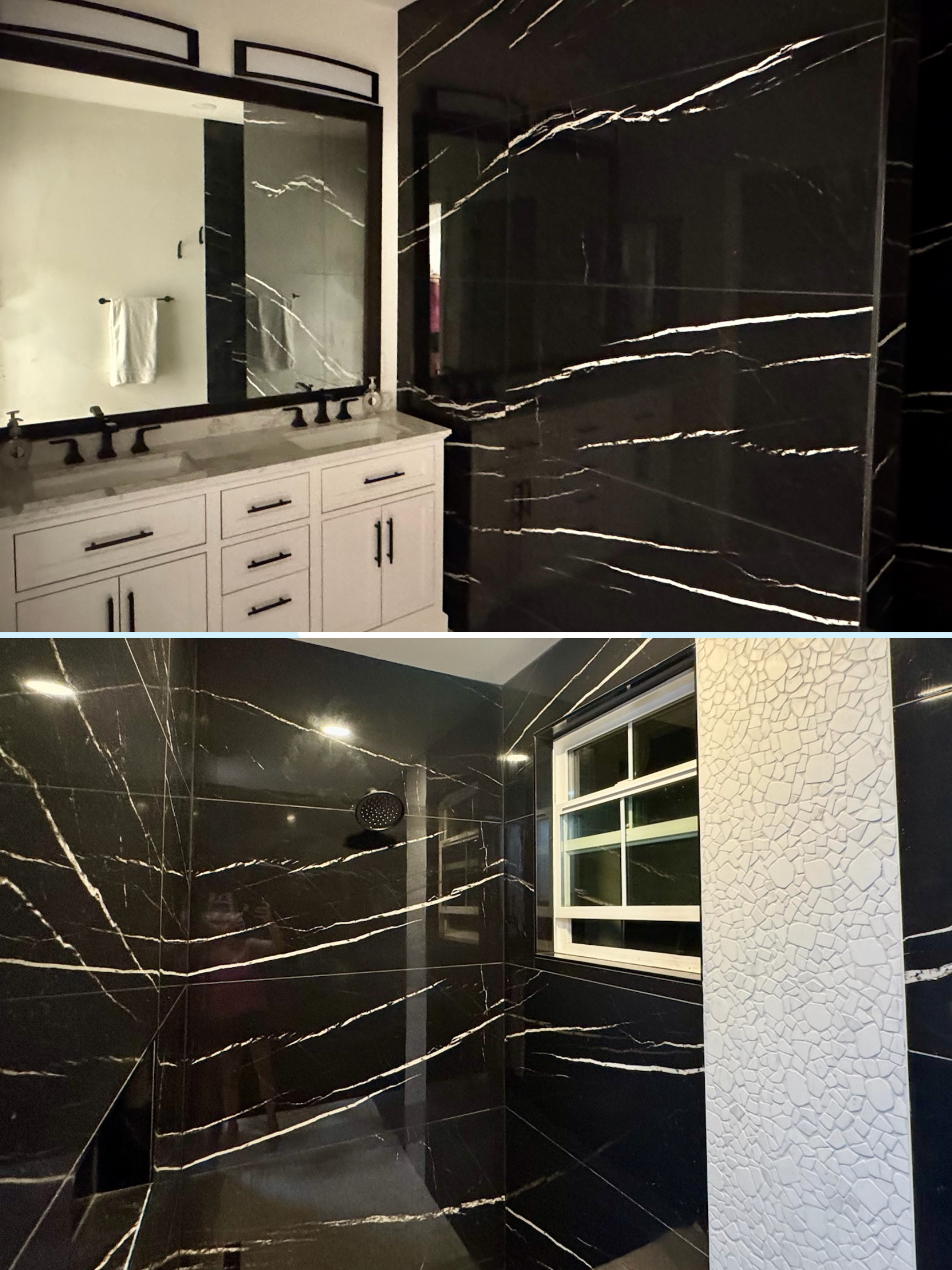 Bathroom with black marble walls and accents, white vanity with black hardware, large mirror, and a window with frosted glass.