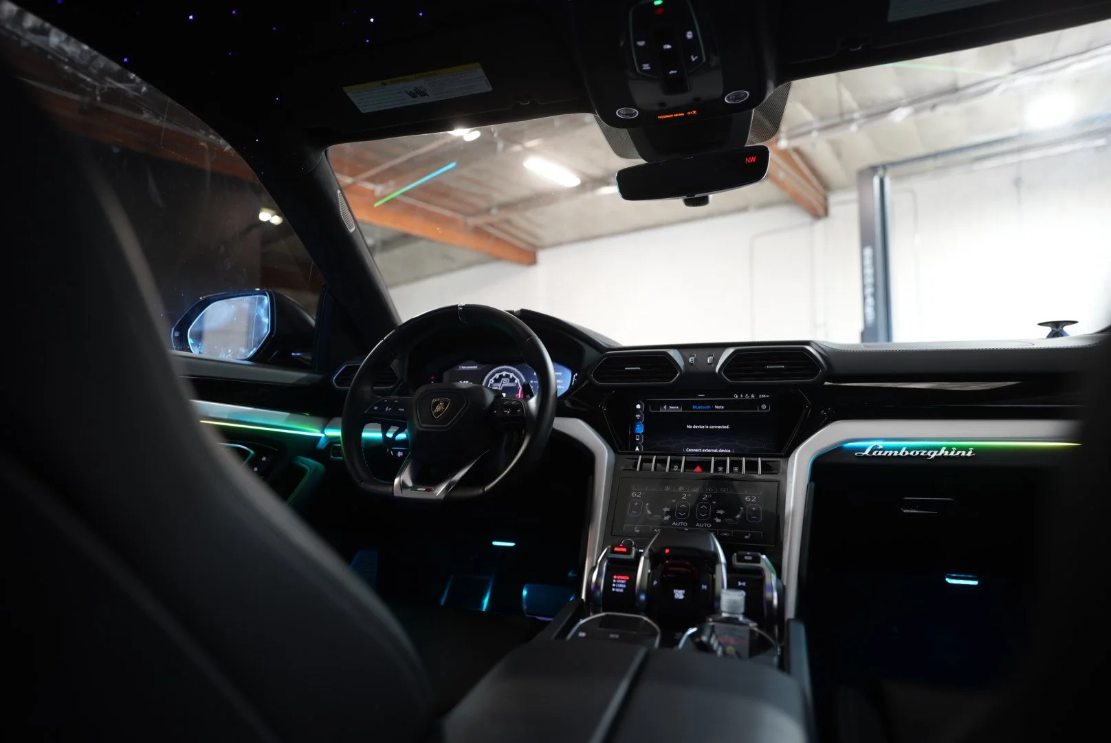 Interior of a Lamborghini Urus sports car showing the dashboard, steering wheel, and central control panel with upgraded illuminated accents installed.