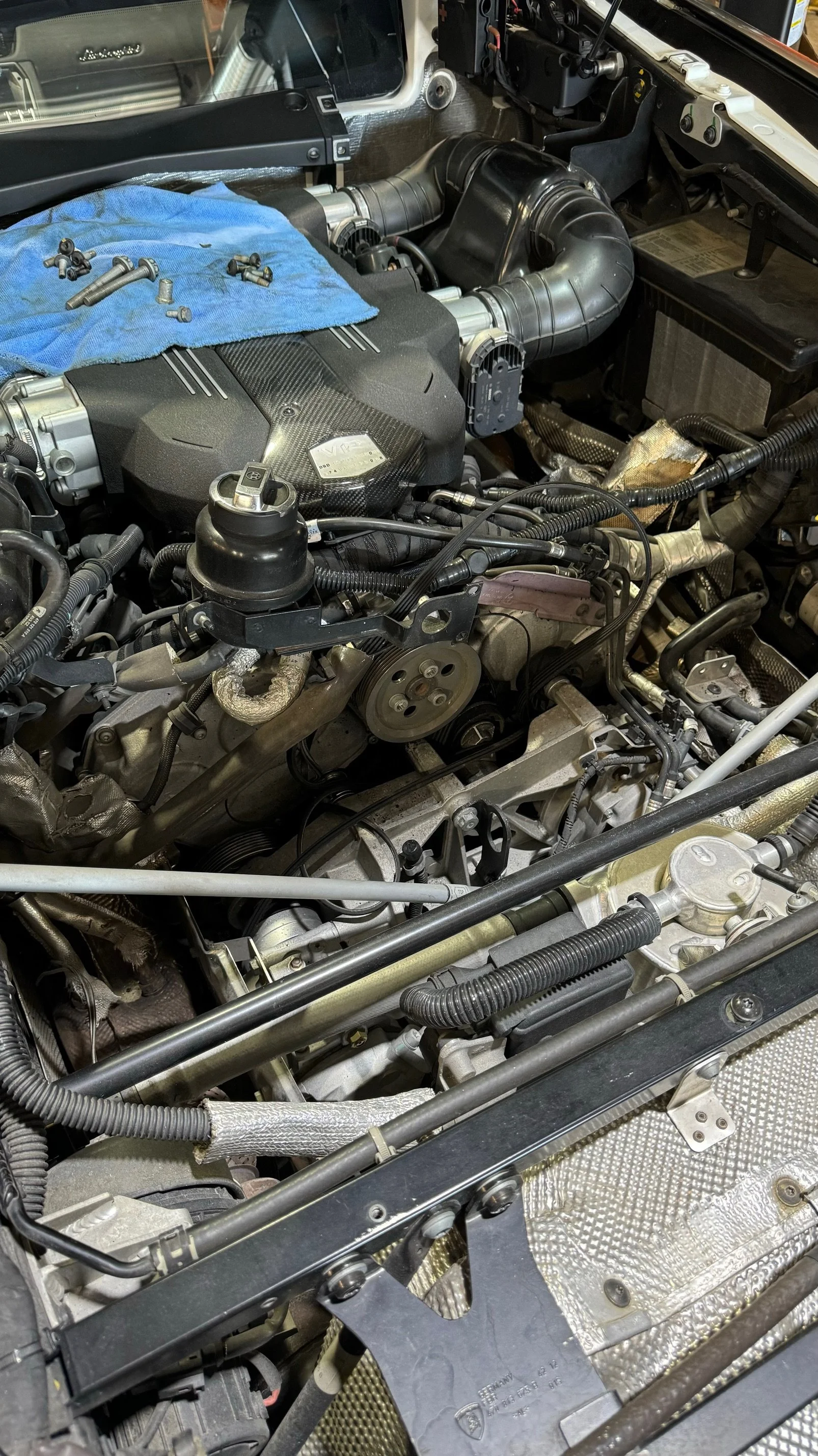 Lamborghini engine bay stripped for repair at Custom Luxury Lab in Frisco, TX, with removed hardware laid out on a shop towel