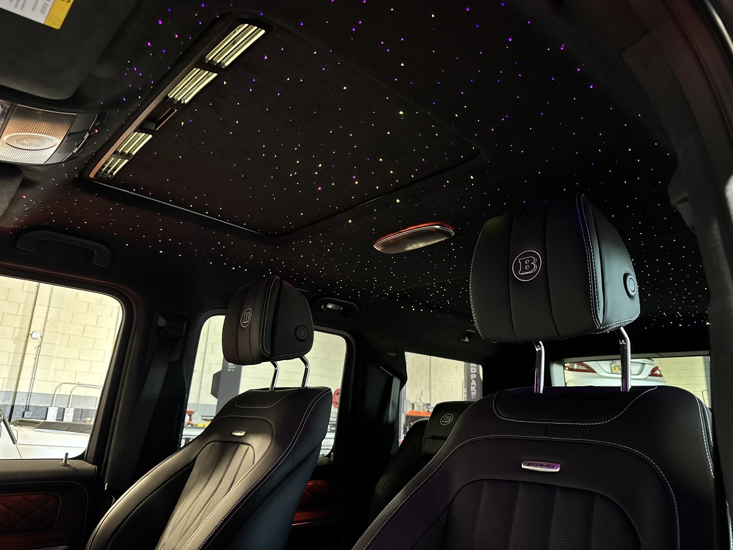 Mercedes-Benz G63 luxury car interior with black leather seats, newly retro-fitted with illuminated starry sky ceiling, and additional luxury features.