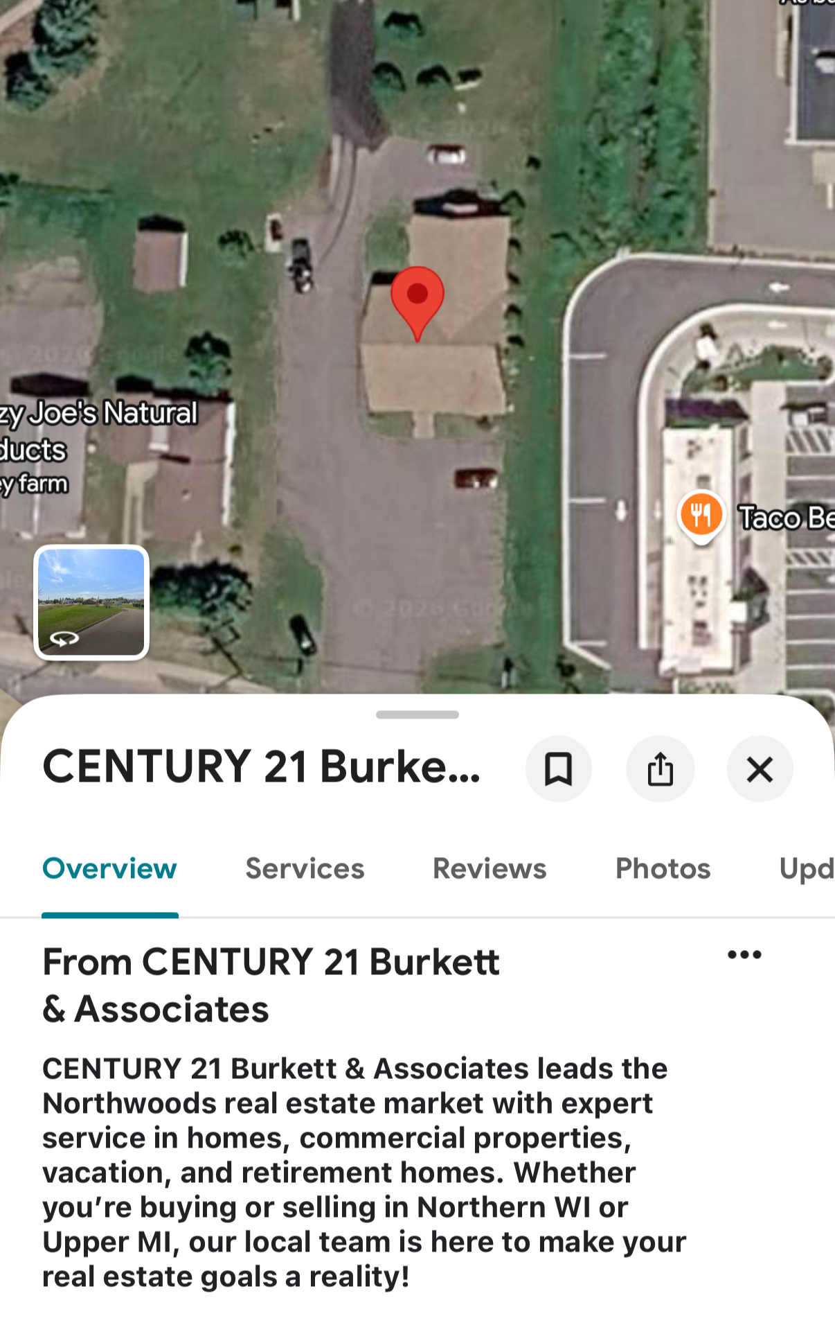 Satellite view of a commercial property with a small building, parking lot, surrounding green space, and nearby streets, with a Taco Bell restaurant visible on the right side.