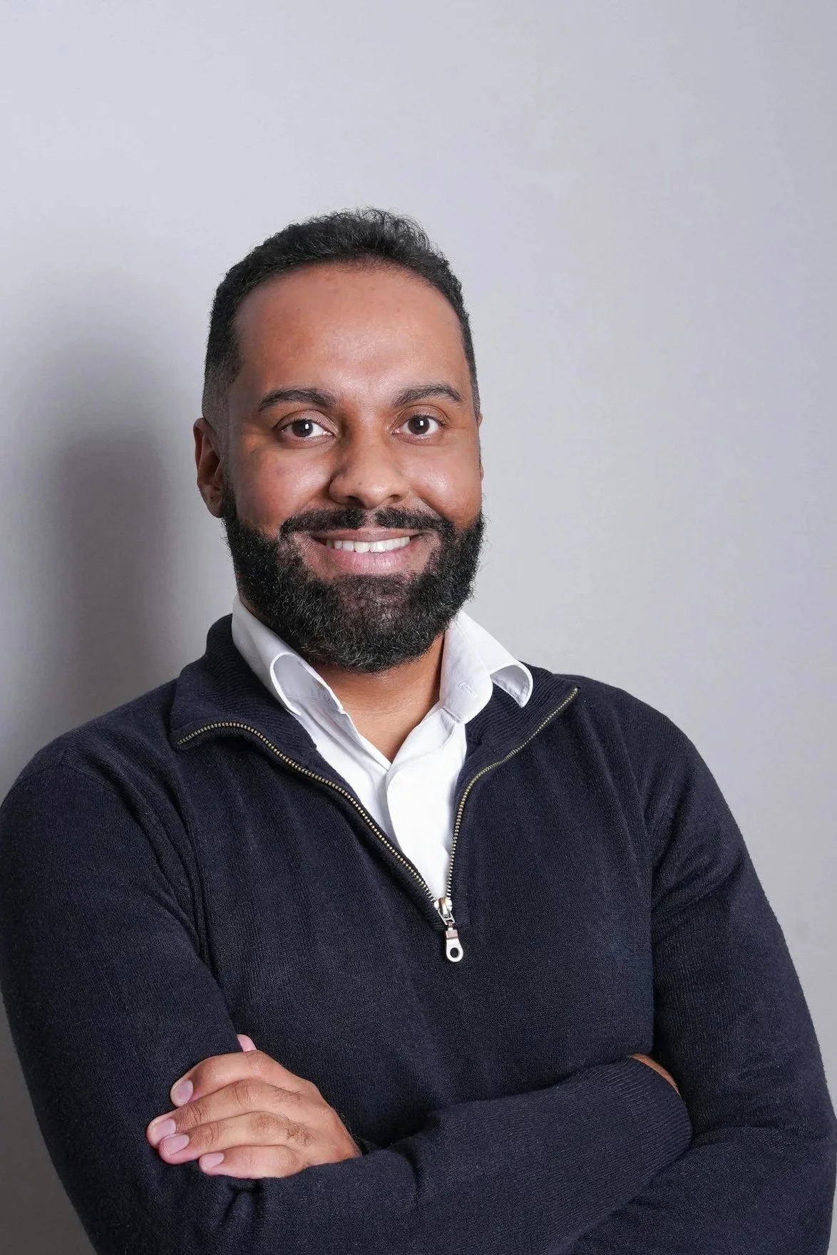 A smiling man with arms crossed facing camera.