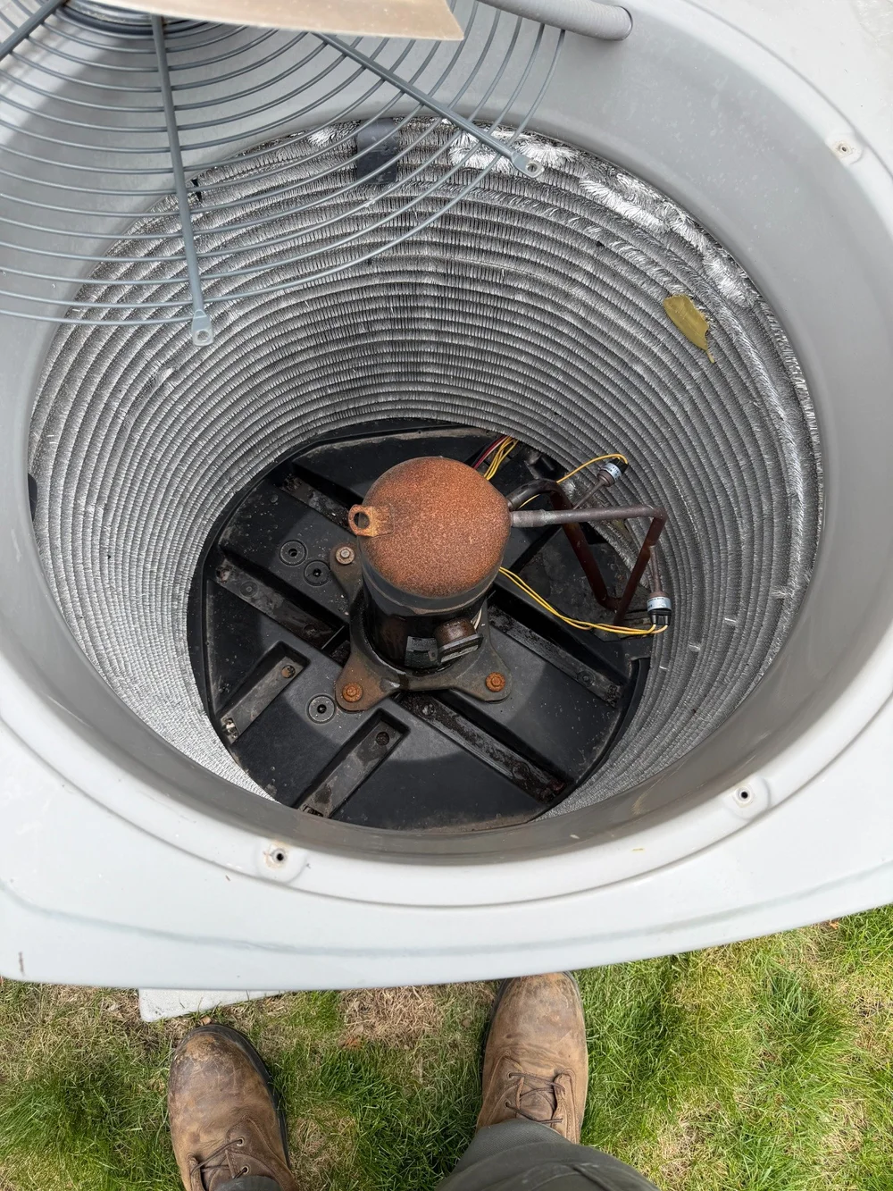 View into an existing outdoor condenser showing the compressor, tubing, and coil.