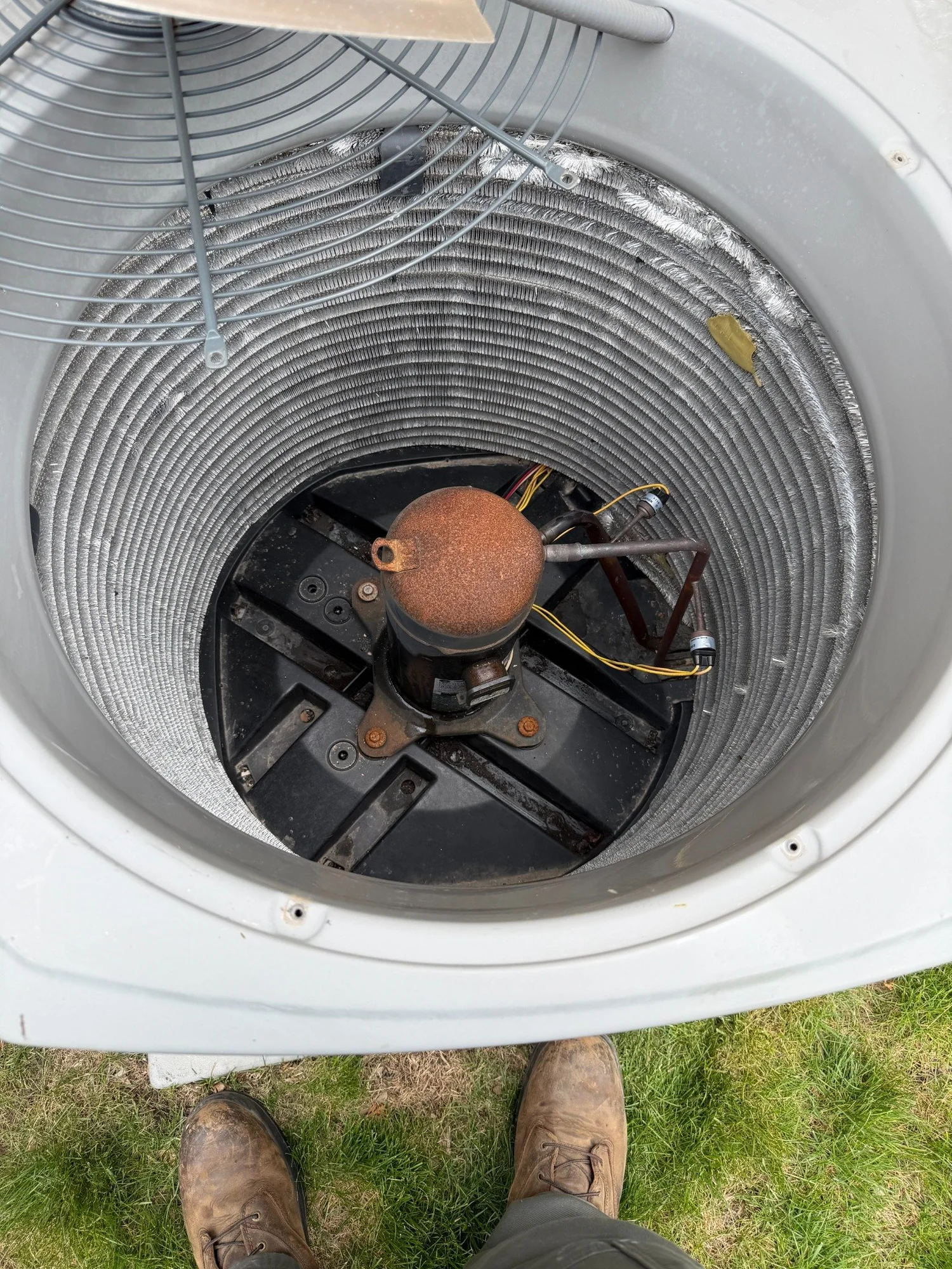 An existing outdoor condenser opened during service, showing its coil, compressor, and tubing.