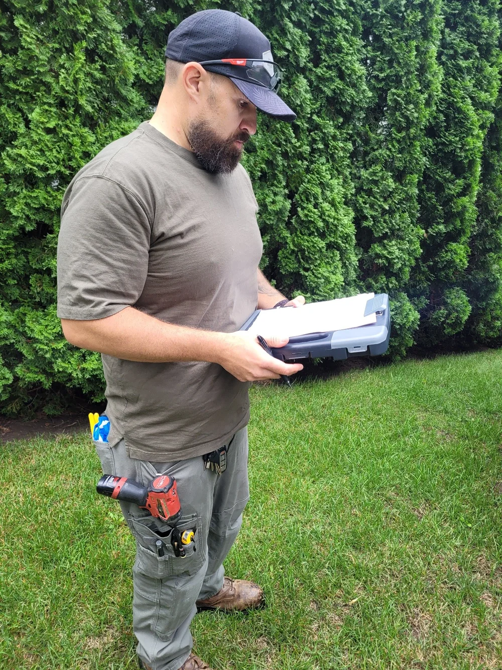 Technician reviewing service paperwork on a clipboard outdoors.