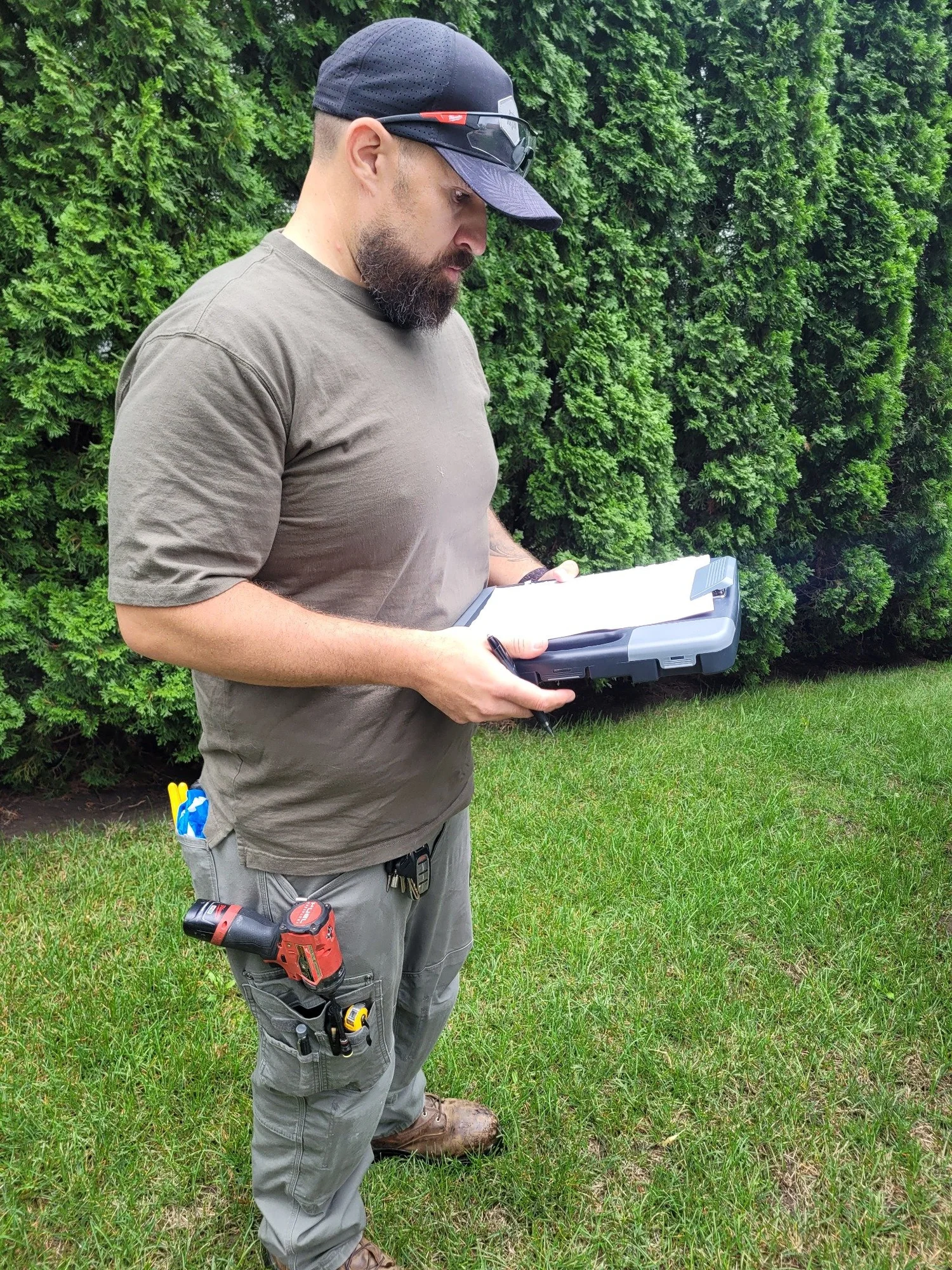 Technician reviewing notes on a clipboard outdoors with service tools.