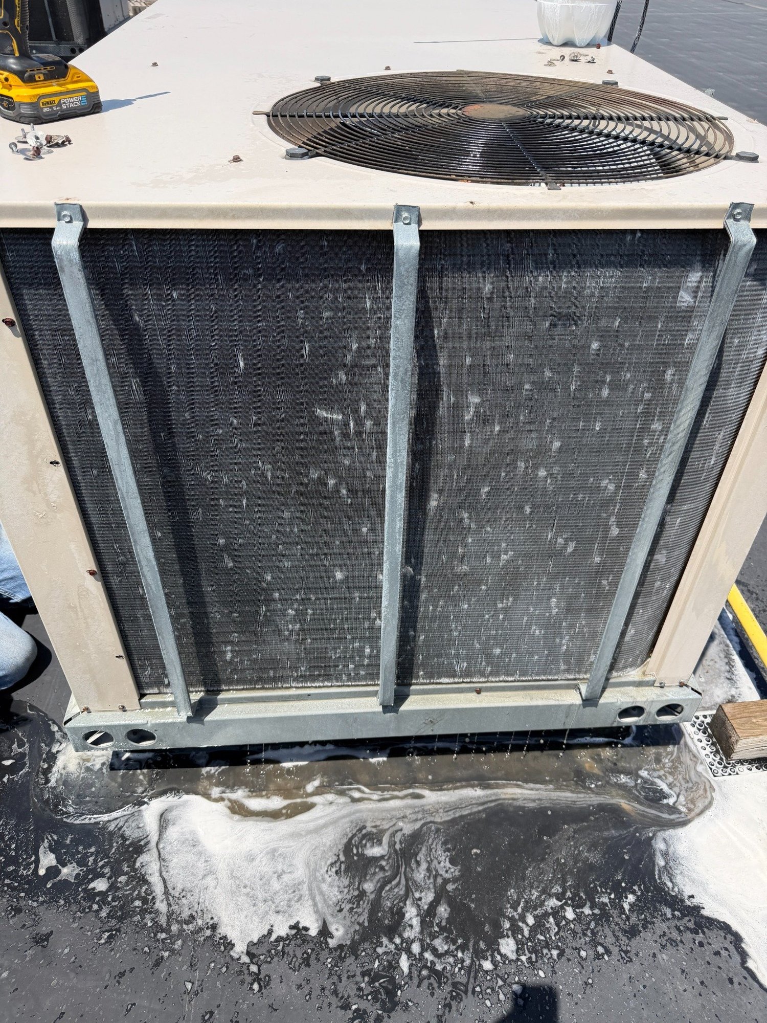 Outdoor condenser coil during cleaning, with wash water below the equipment.