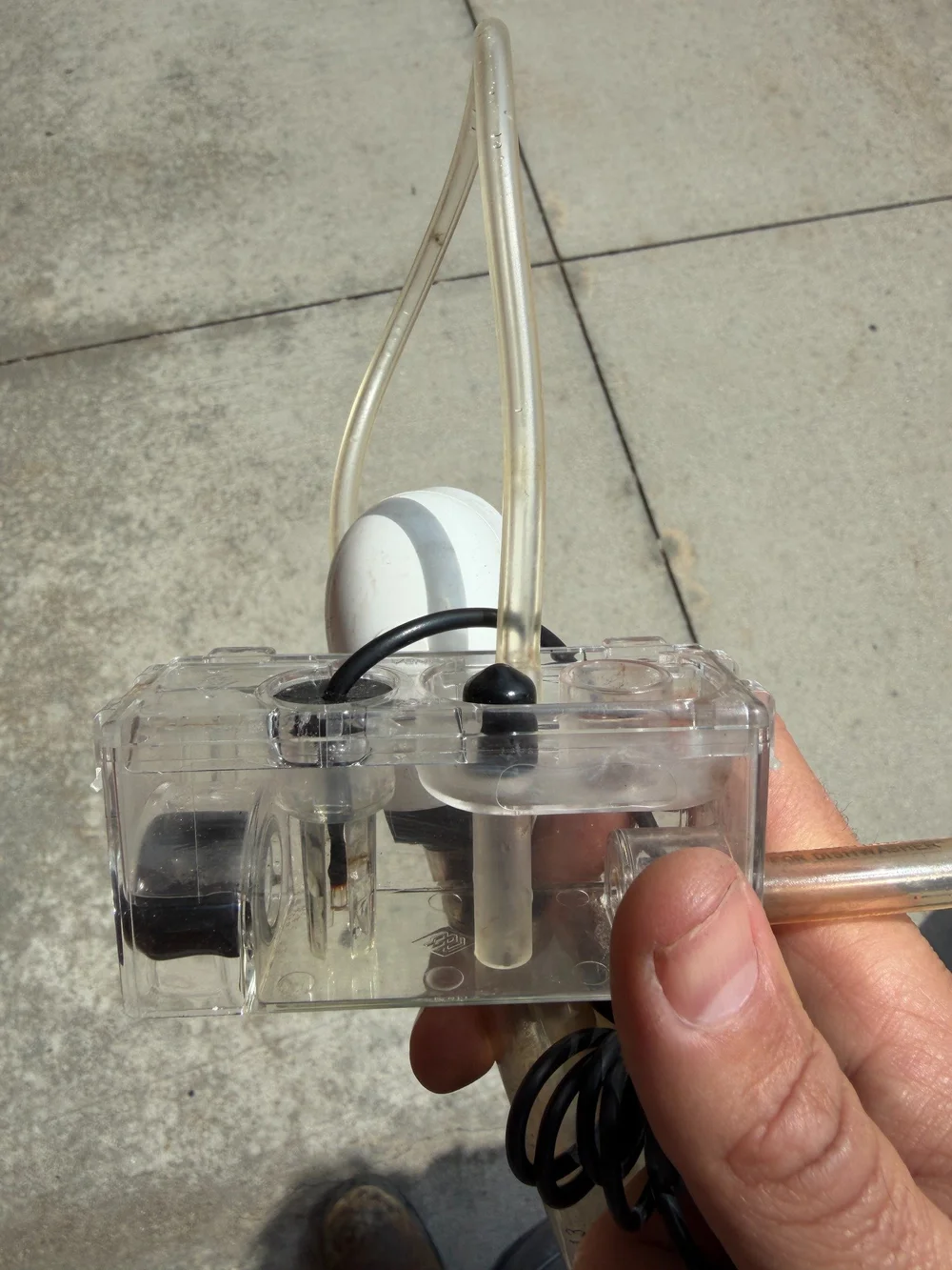 A clear condensate collection and float assembly with connected tubing.