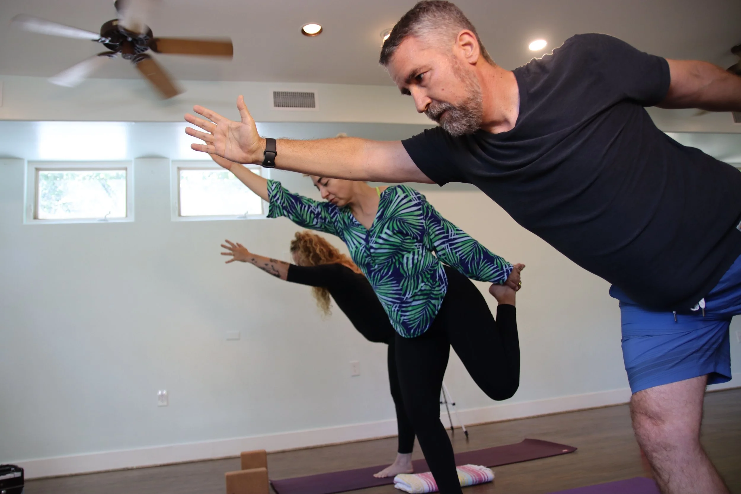 Yoga students practicing Warrior III during a group yoga class in Austin, TX.