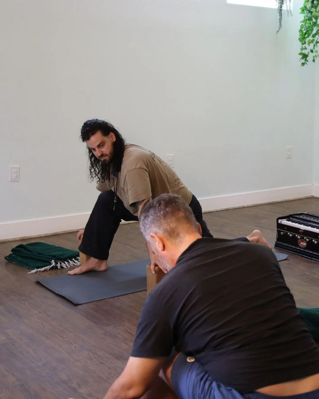 Yoga instructor demonstrating a pose while guiding a student during a private yoga session.