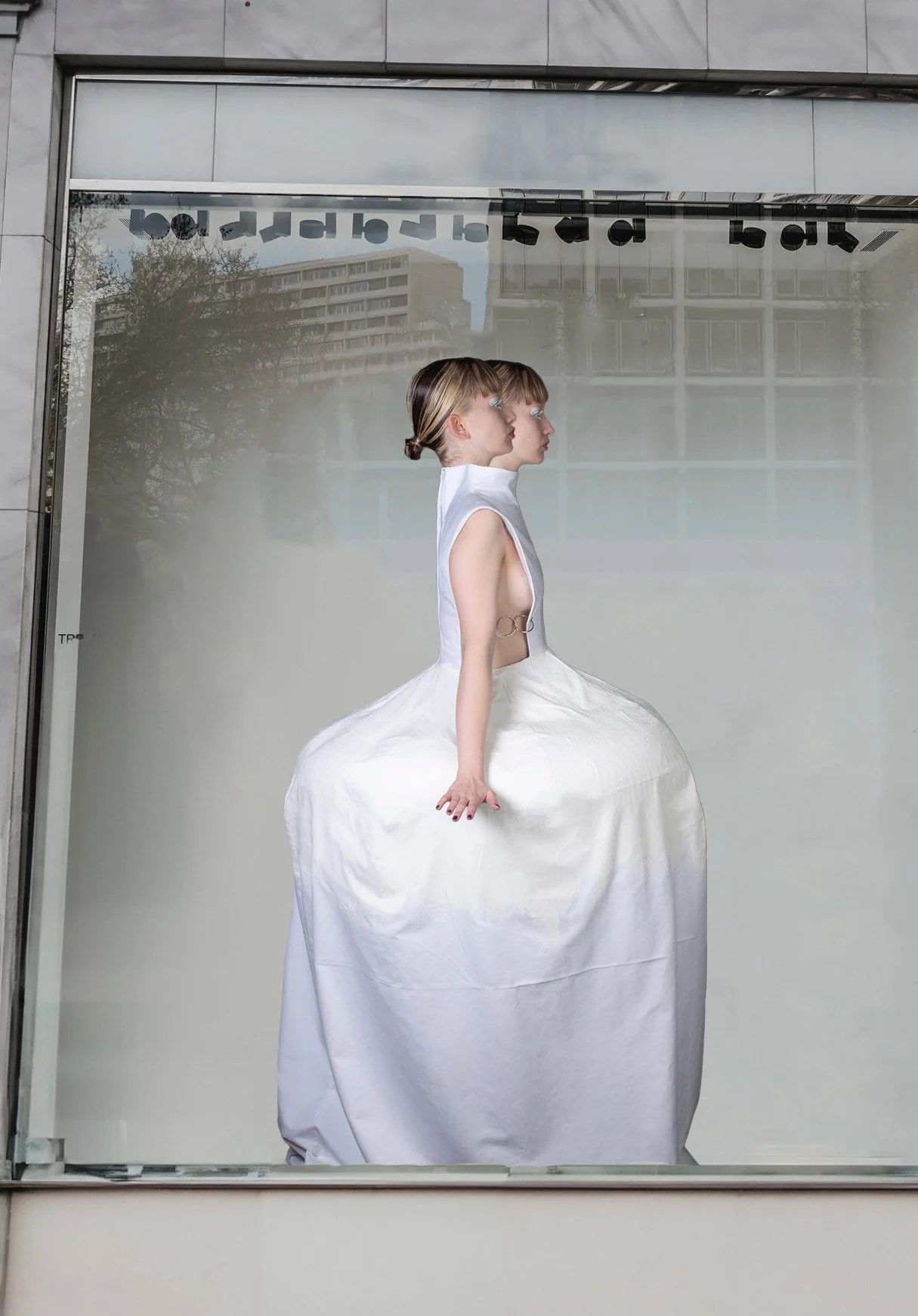 Escaparate con un maniquí que lleva un vestido blanco con una falda muy grande, y lleva un peinado de cabello rubio y corto.