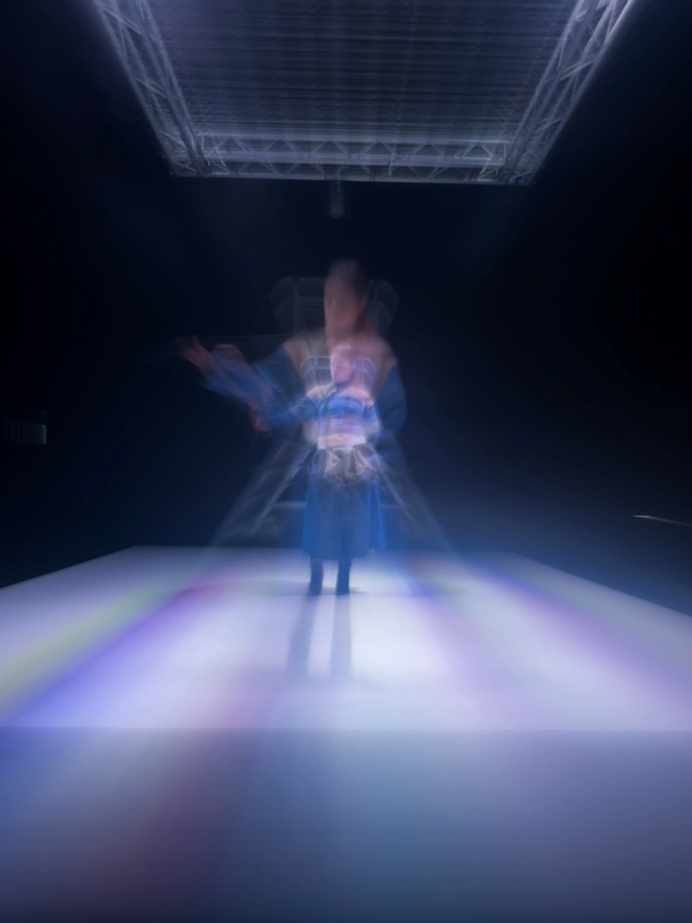 Persona en un entorno oscuro con iluminación azul, vista desde abajo, con estructura metálica encima y efecto de movimiento.