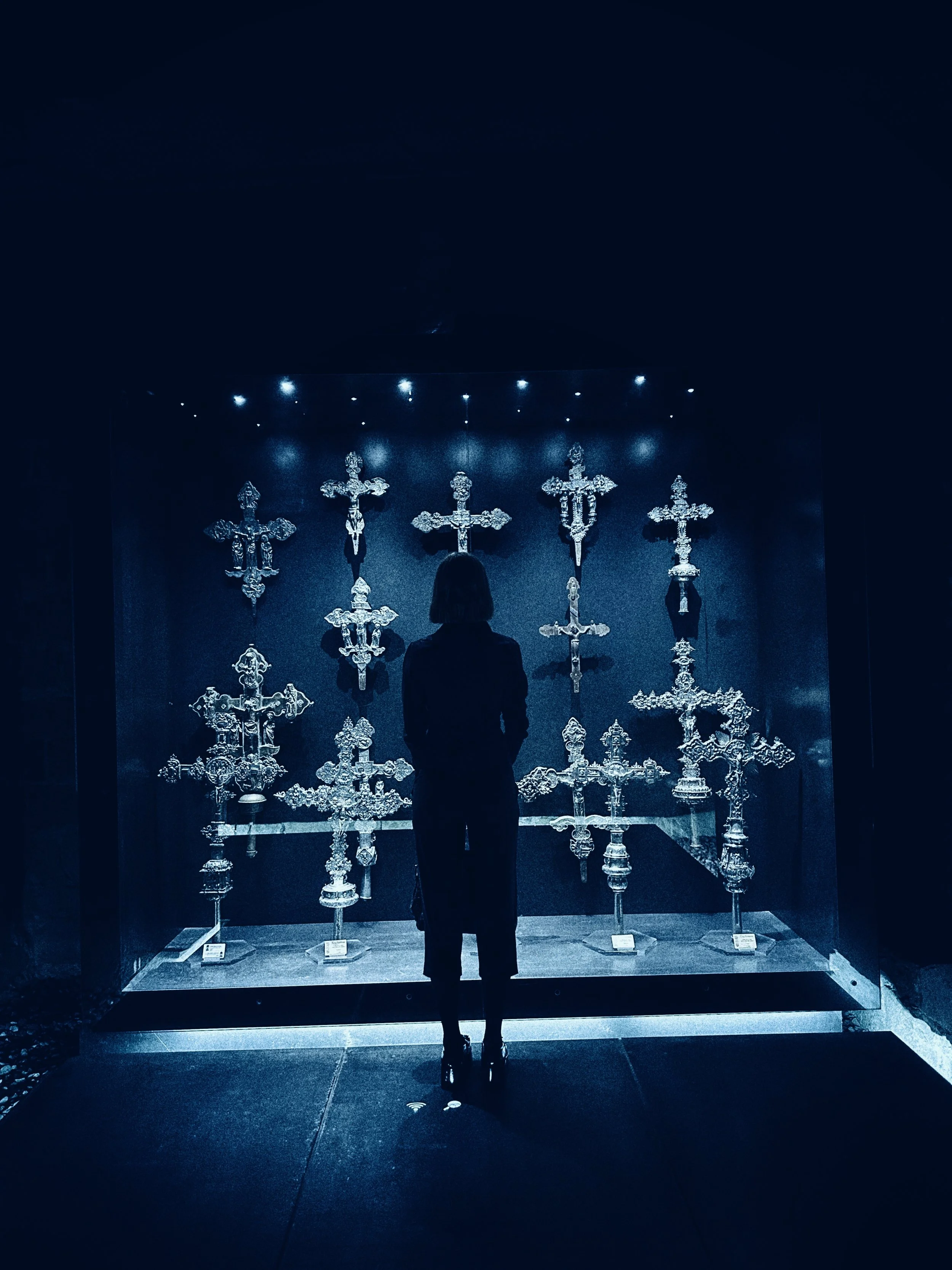 Persona observando una exhibición de candelabros de oro en un museo.