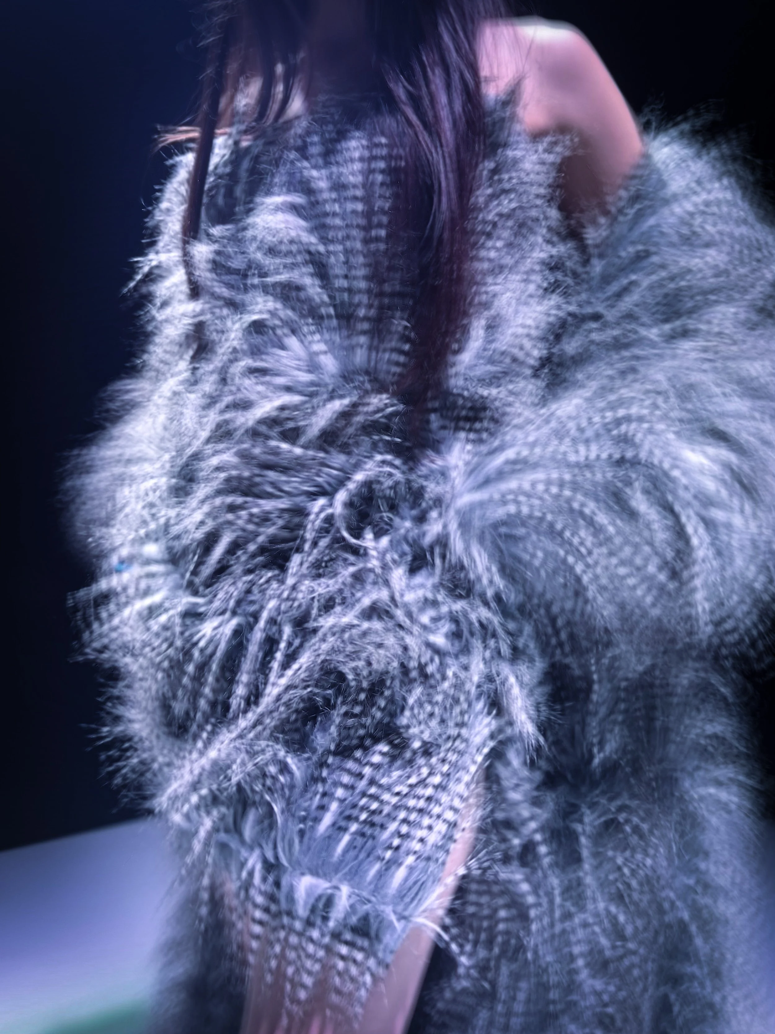 Una persona con cabello largo y oscuro cubierto parcialmente por burbujas de jabón, en un fondo oscuro.